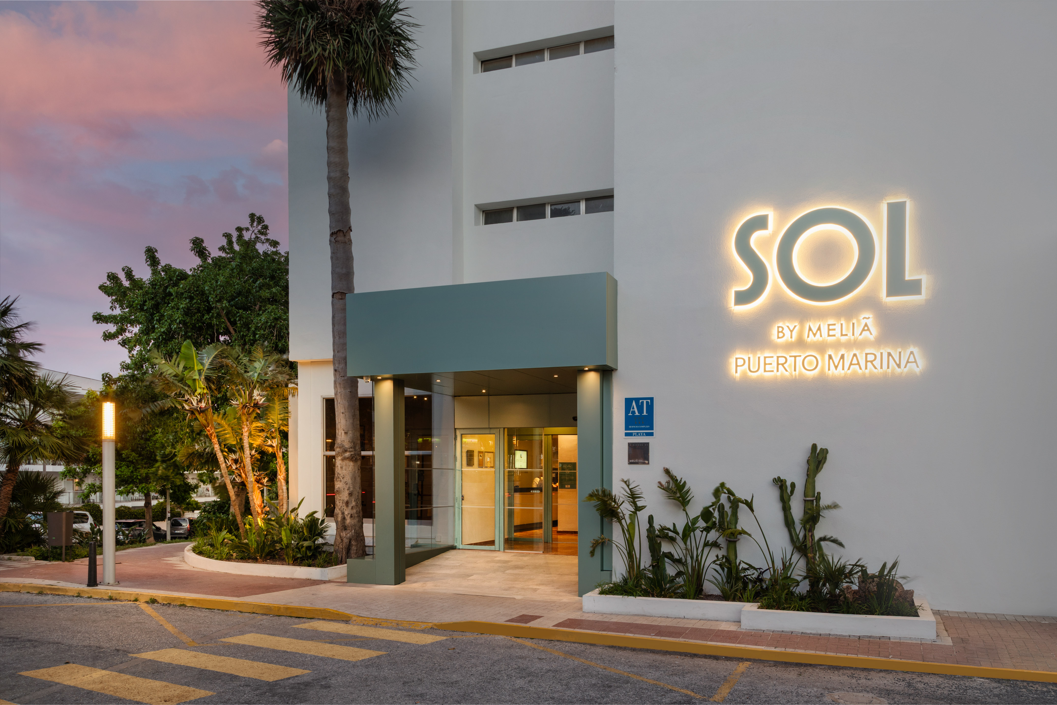 Sol by Meliá Puerto Marina hotel exterior, illuminated sign at dusk.