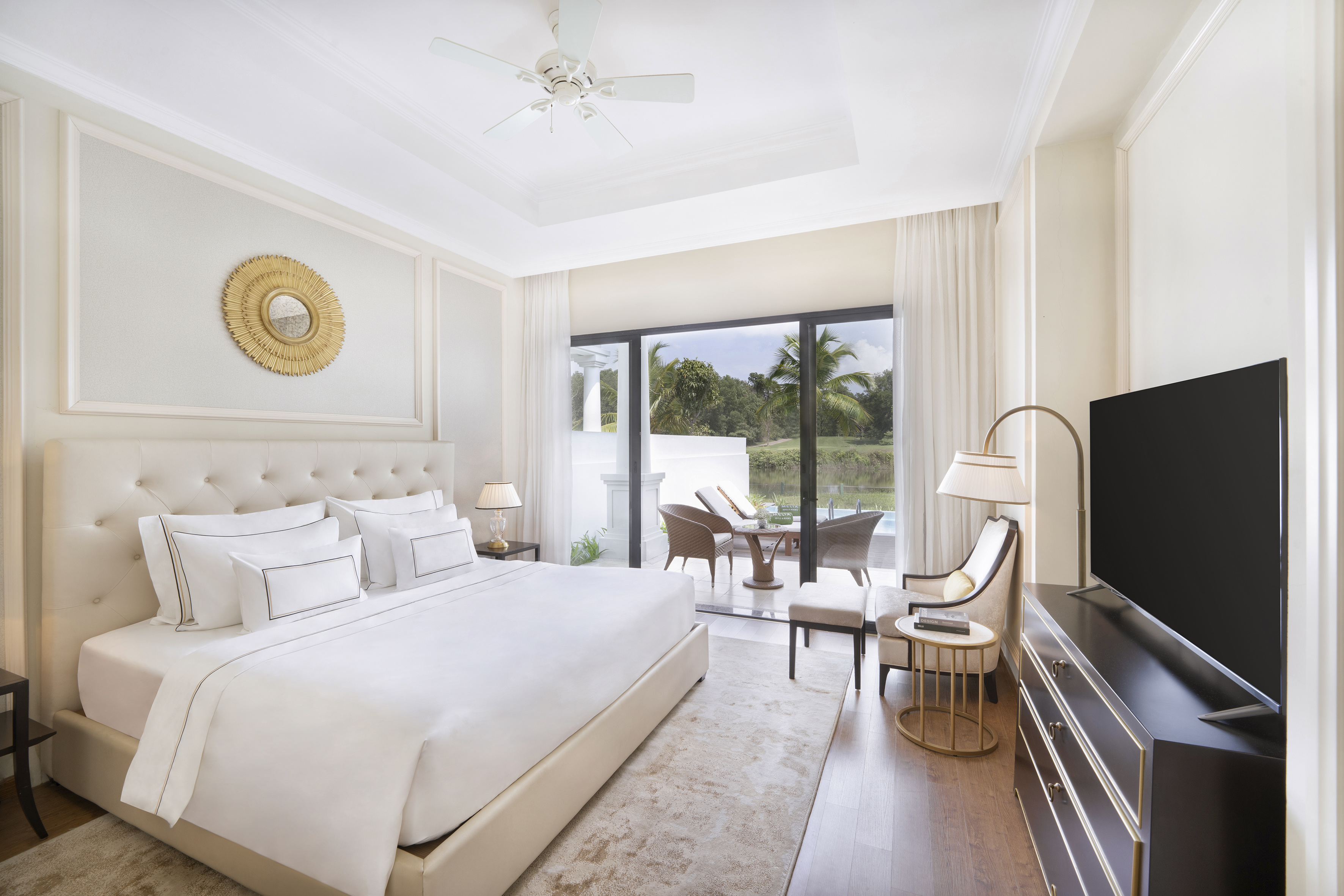 Luxury bedroom with king bed, patio, and golf course view.
