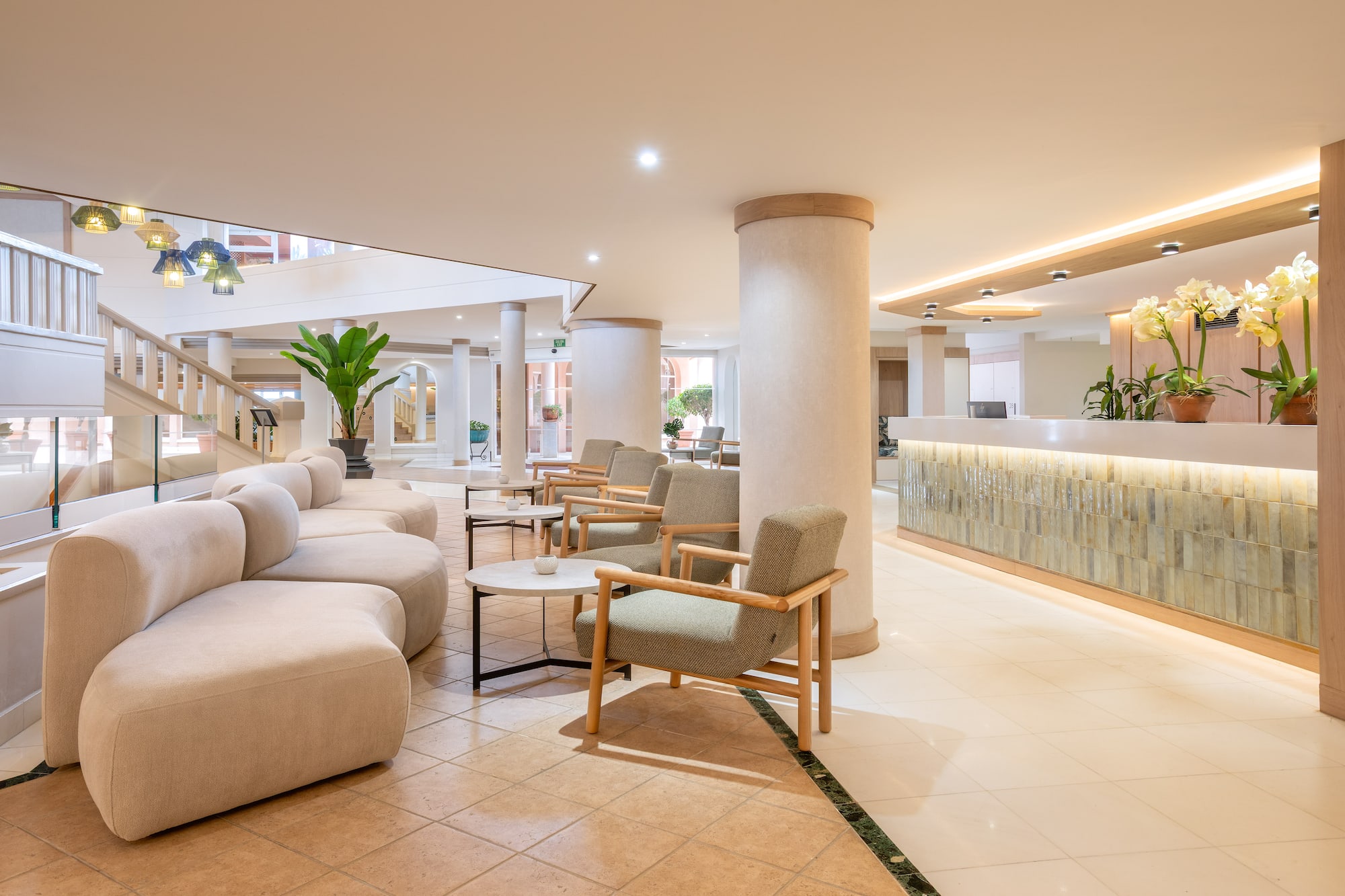 Modern hotel lobby with curved sofa, stylish seating, and bright reception.