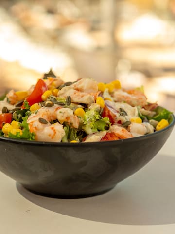 a bowl of salad with shrimp and corn