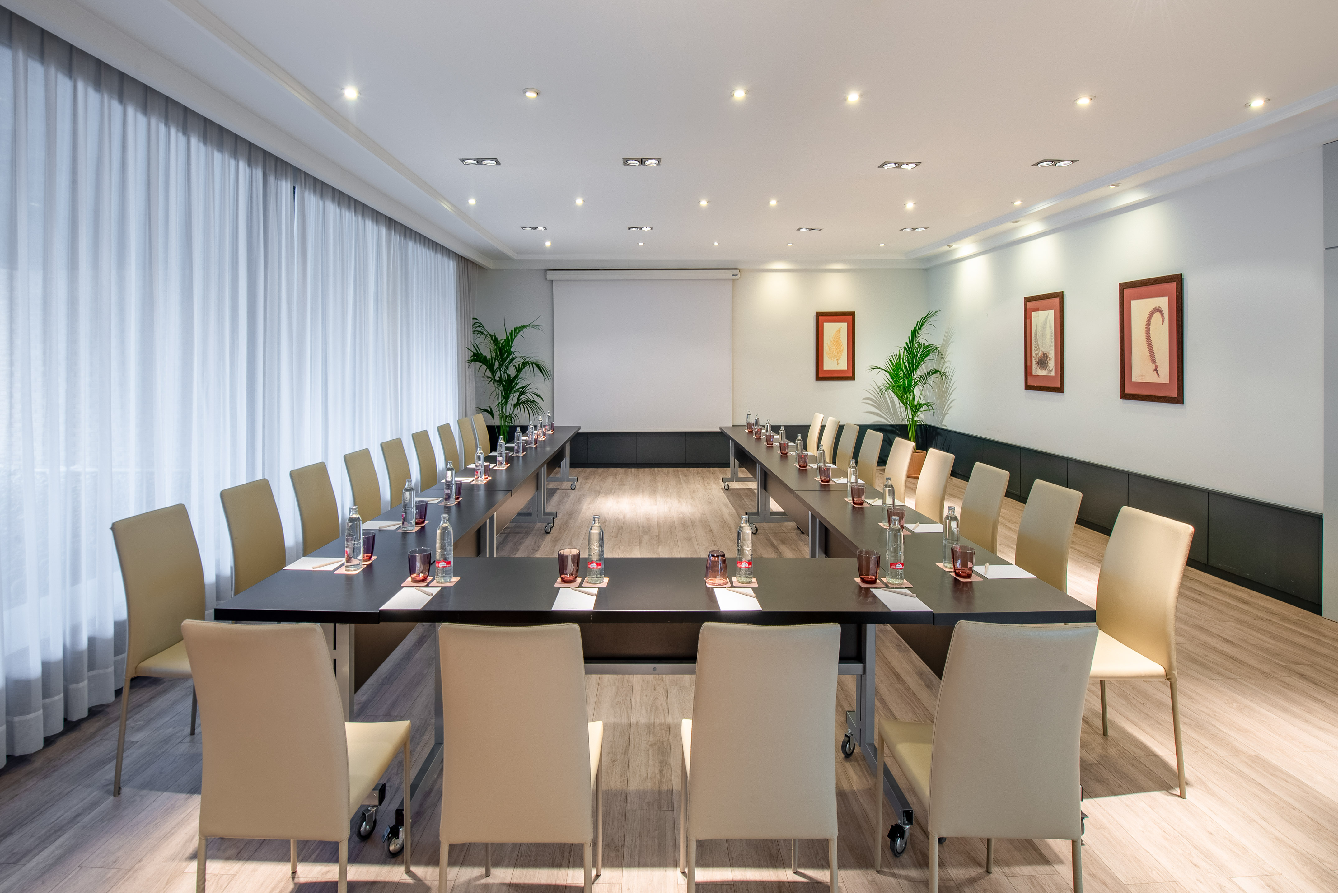 Modern U-shaped meeting room setup with projector screen for corporate events.