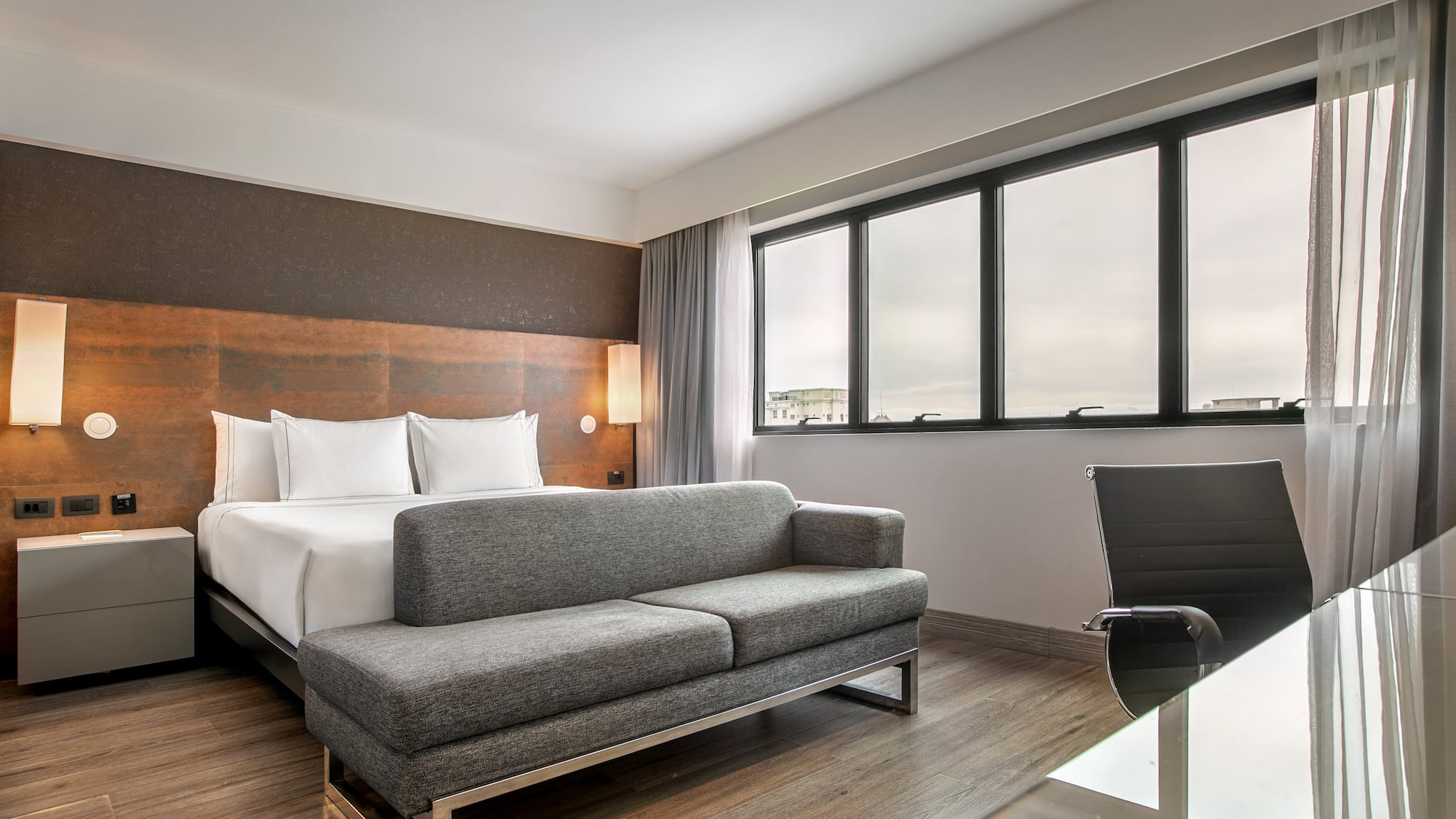 Quarto de hotel moderno com cama de casal, sofá cinza e escrivaninha. - Grand Premium - Meliá Ibirapuera, São Paulo
