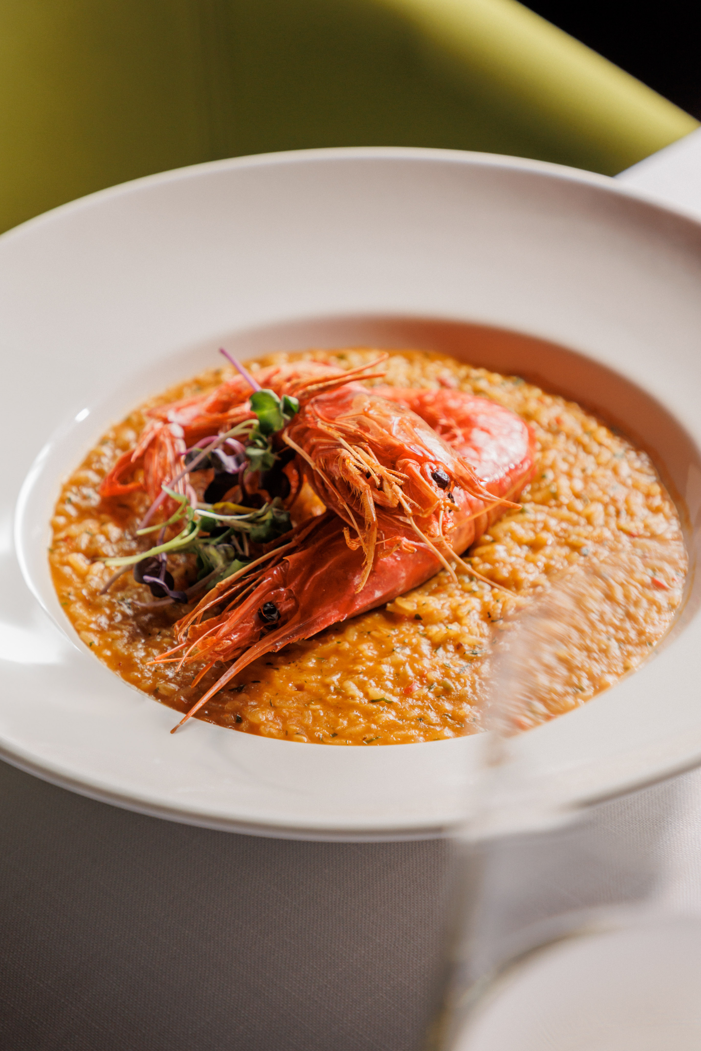 Seafood risotto with two large, whole red prawns and green garnish.