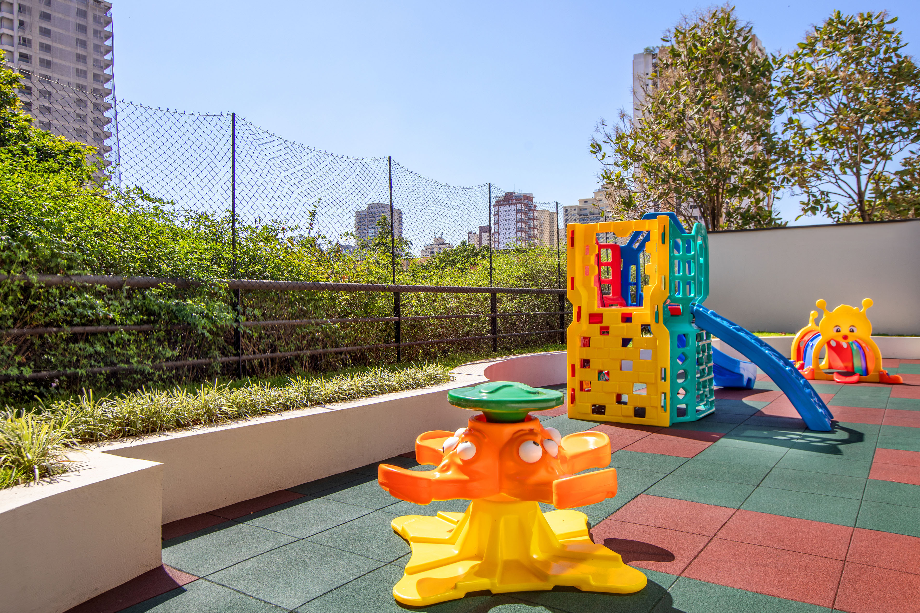 Colorful outdoor playground with slide, spring rider, and safety tiles.