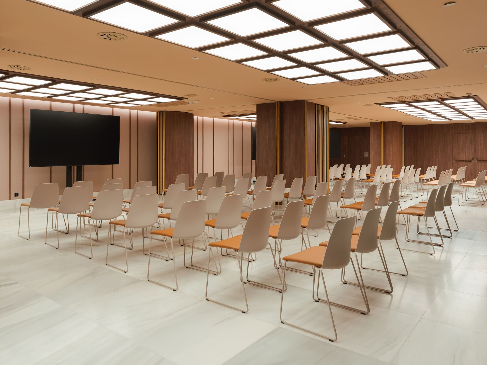 Empty modern conference room with rows of chairs and a large presentation screen.
