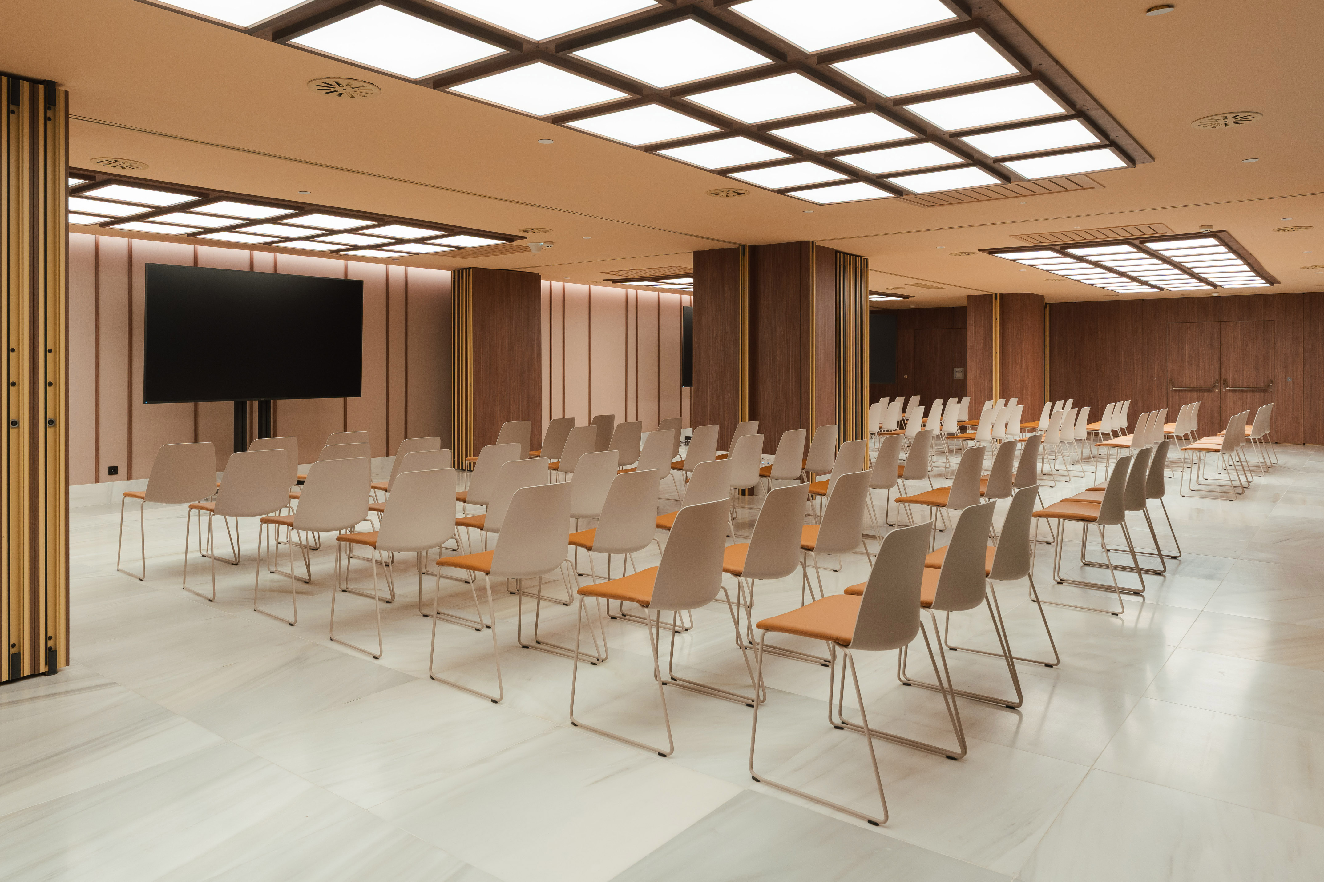 Empty modern conference room with rows of chairs and a large presentation screen.
