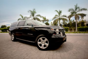 a black suv parked on brick road with palm trees in the background