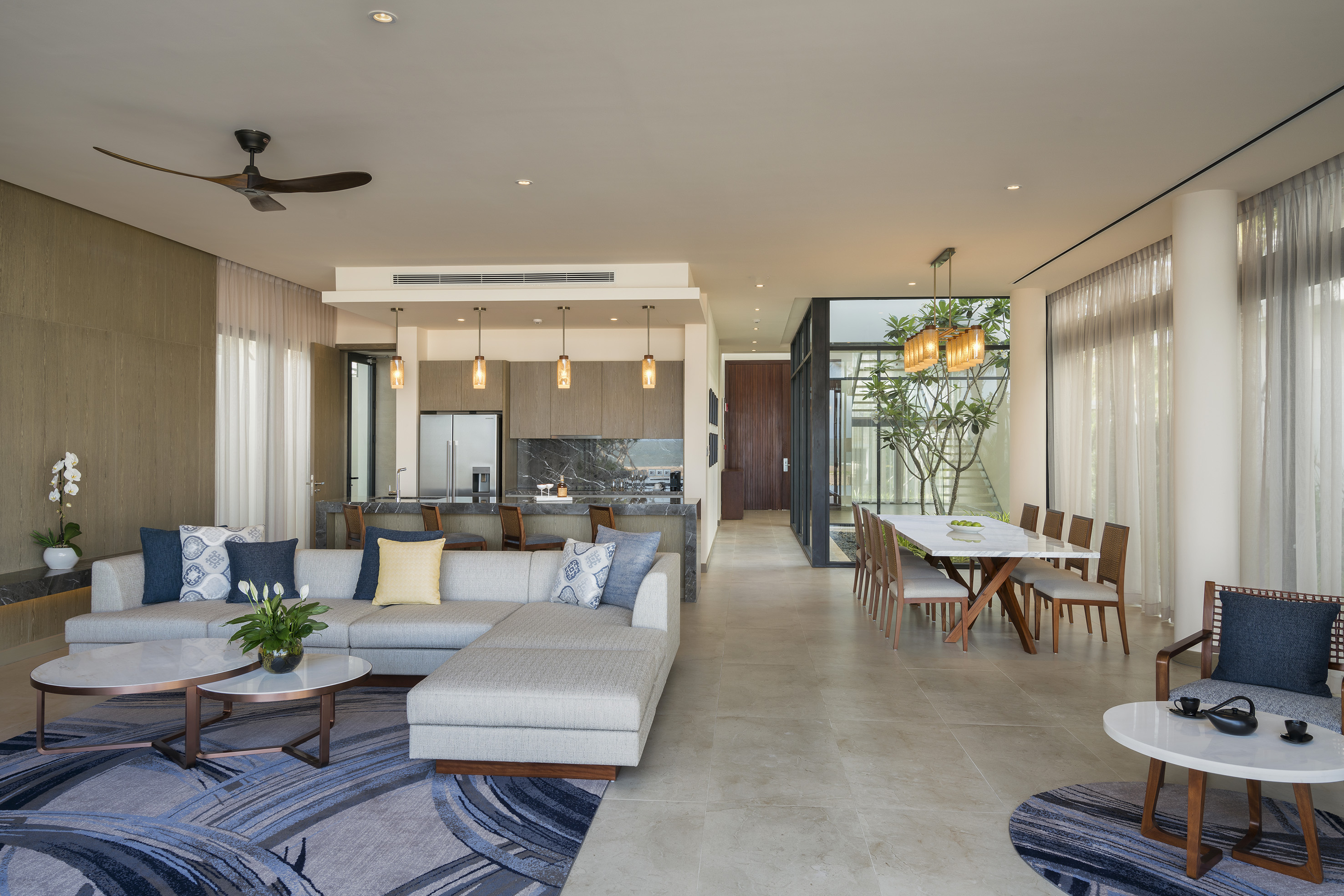 Modern open plan living, kitchen, dining area with sleek furniture.