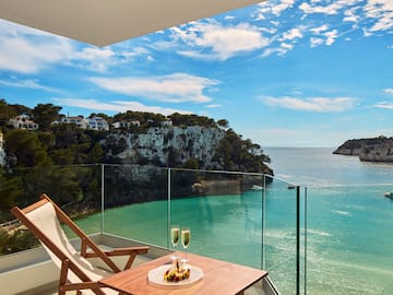 a table with two glasses of champagne on it overlooking a body of water