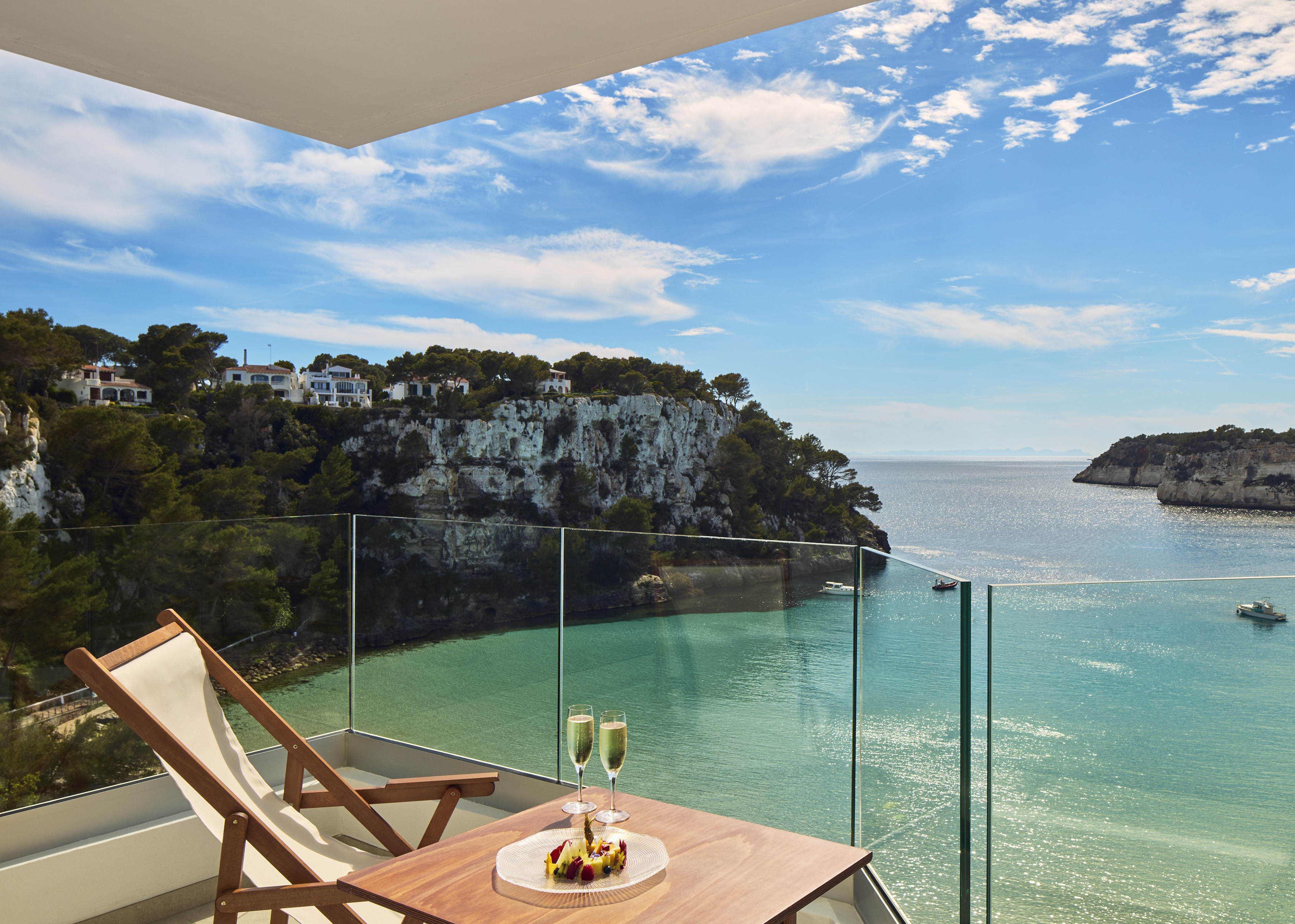 Balcony with champagne, fruit, overlooking turquoise bay and cliffside villas.