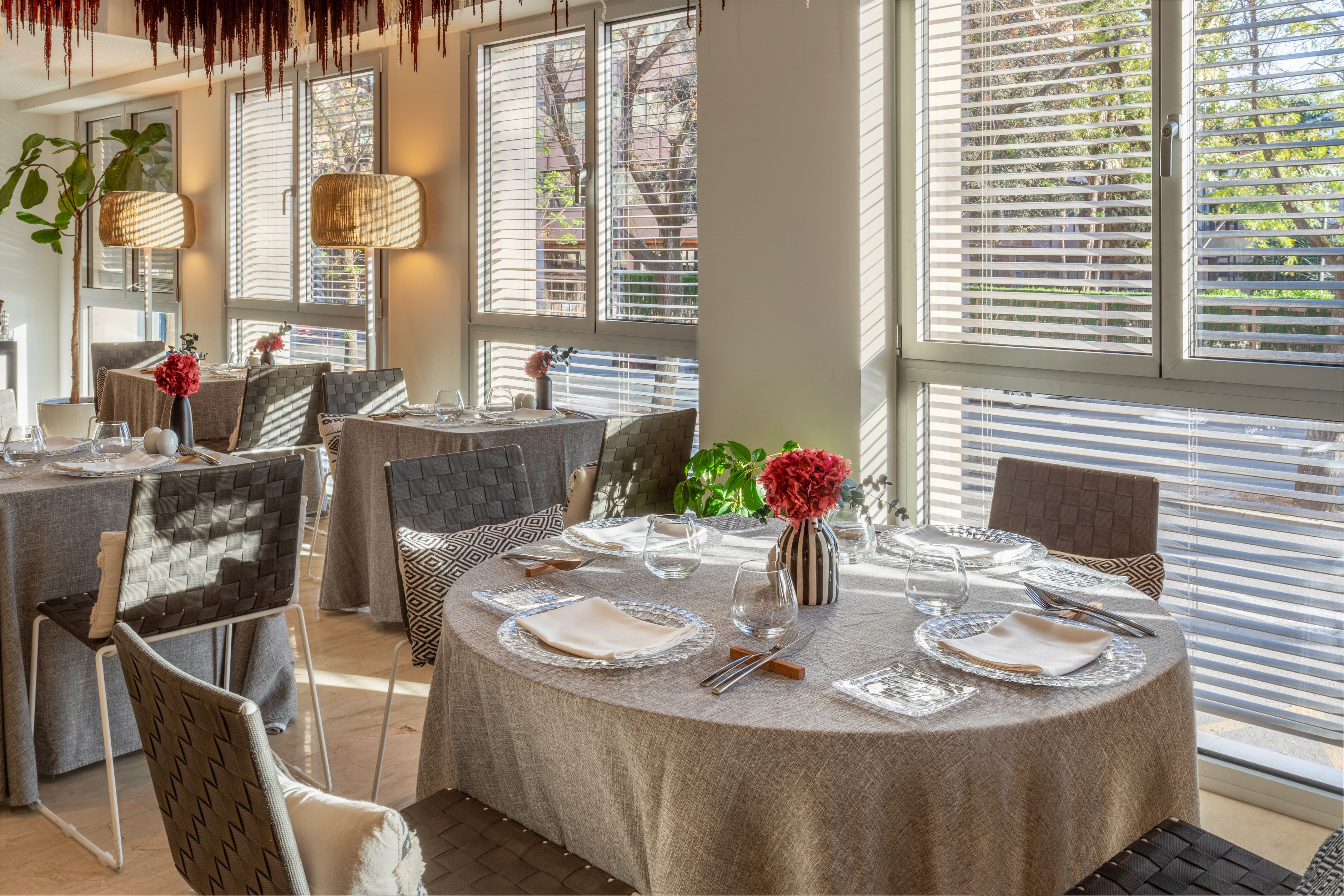 Elegant restaurant dining room with set tables, modern chairs, and bright windows.