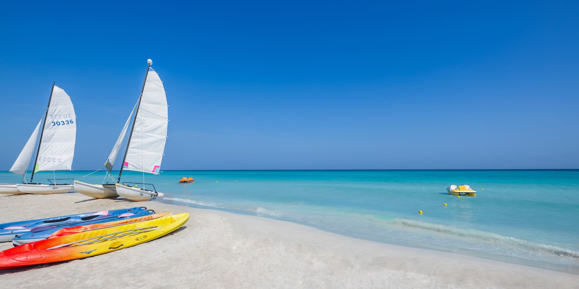 a sailboat and kayaks on a beach