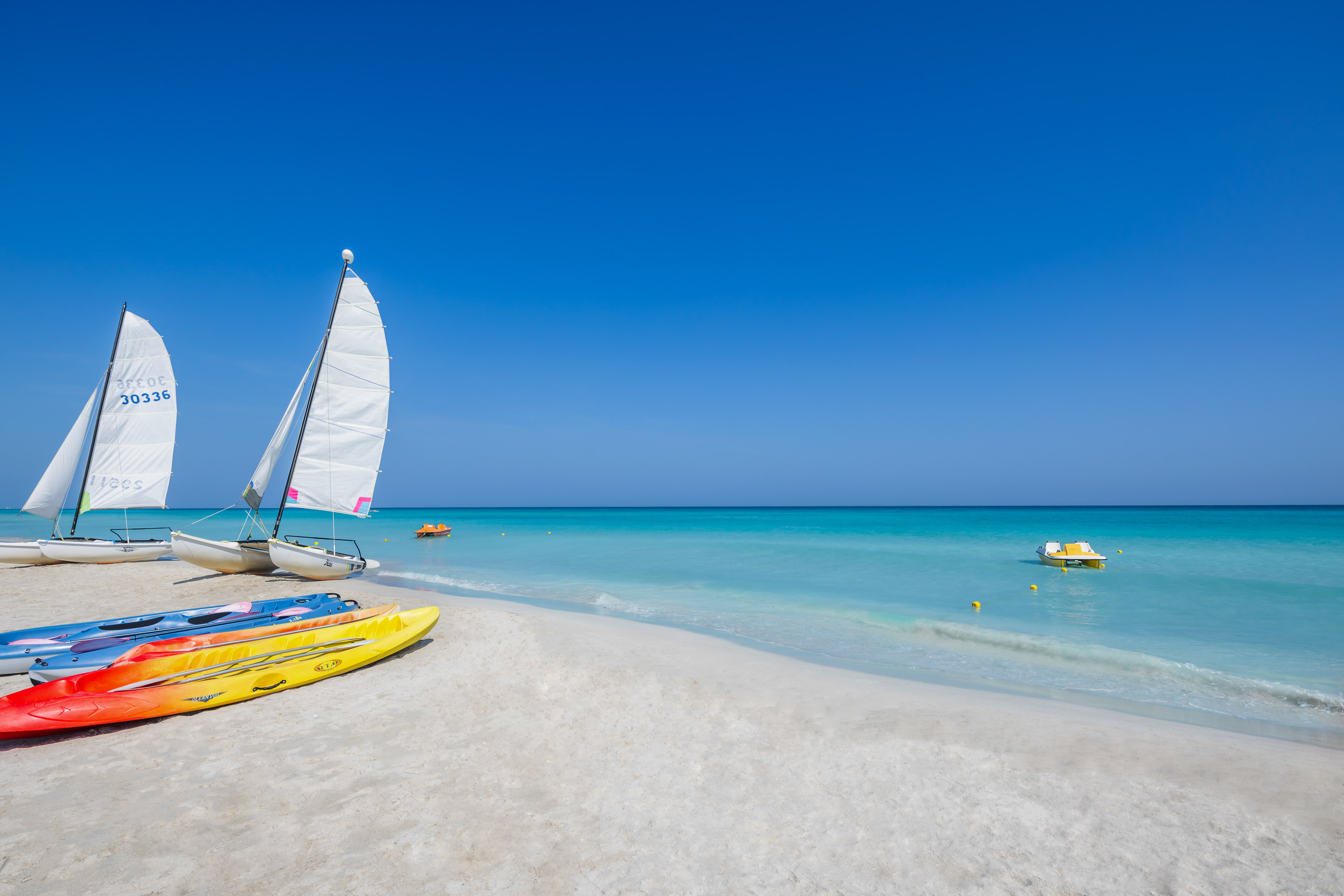 a sailboat and kayaks on a beach