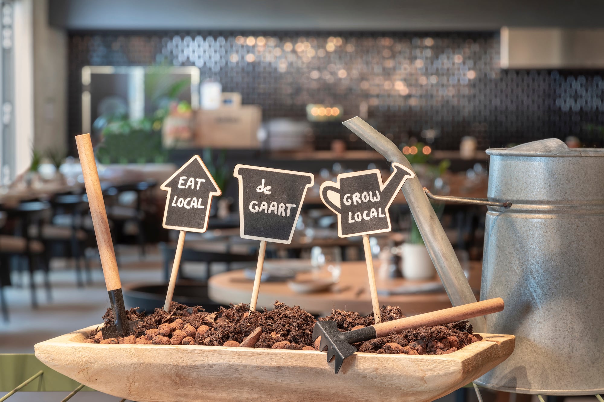 Cafe display with "Eat Local" and "Grow Local" signs, soil, and garden tools.