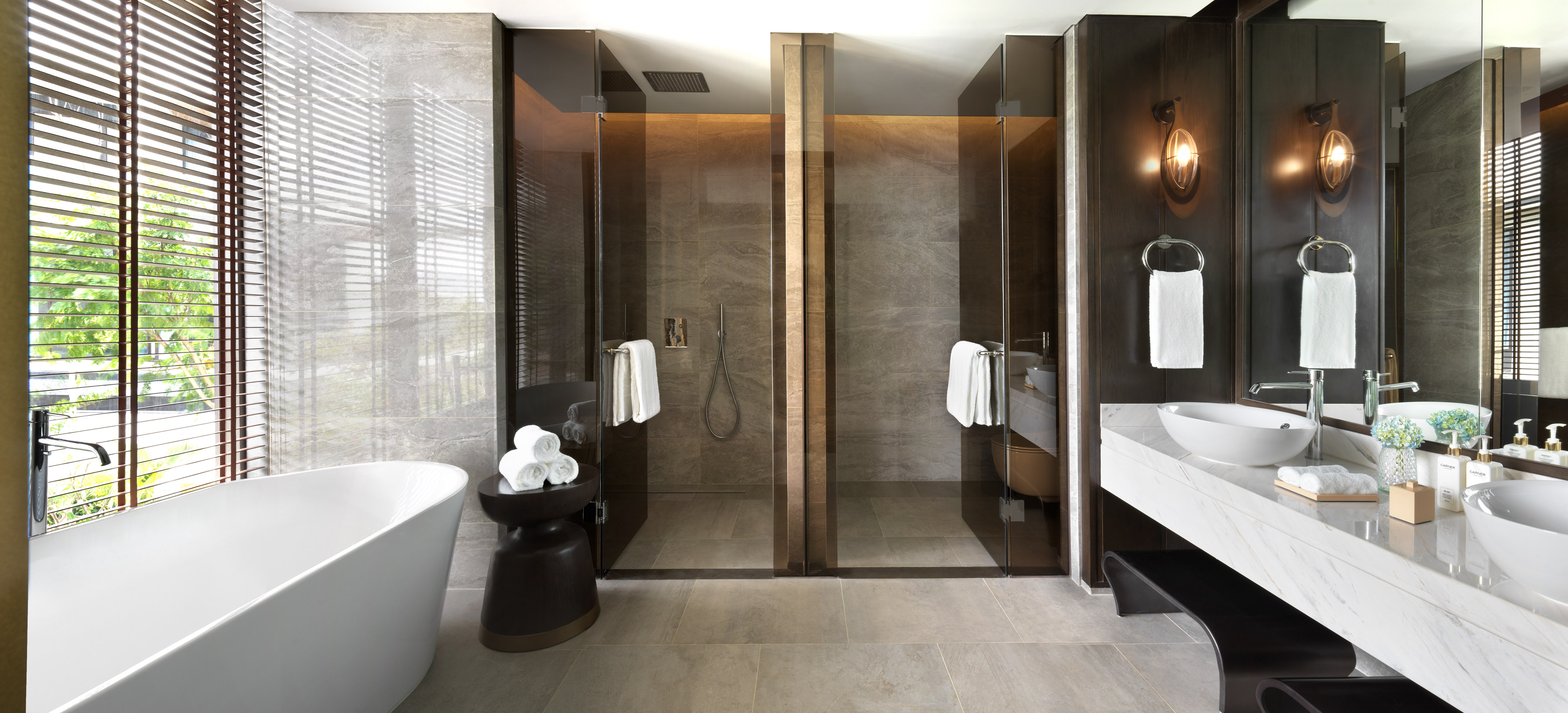 Modern luxury bathroom with freestanding tub, dual glass showers, and double vanity.