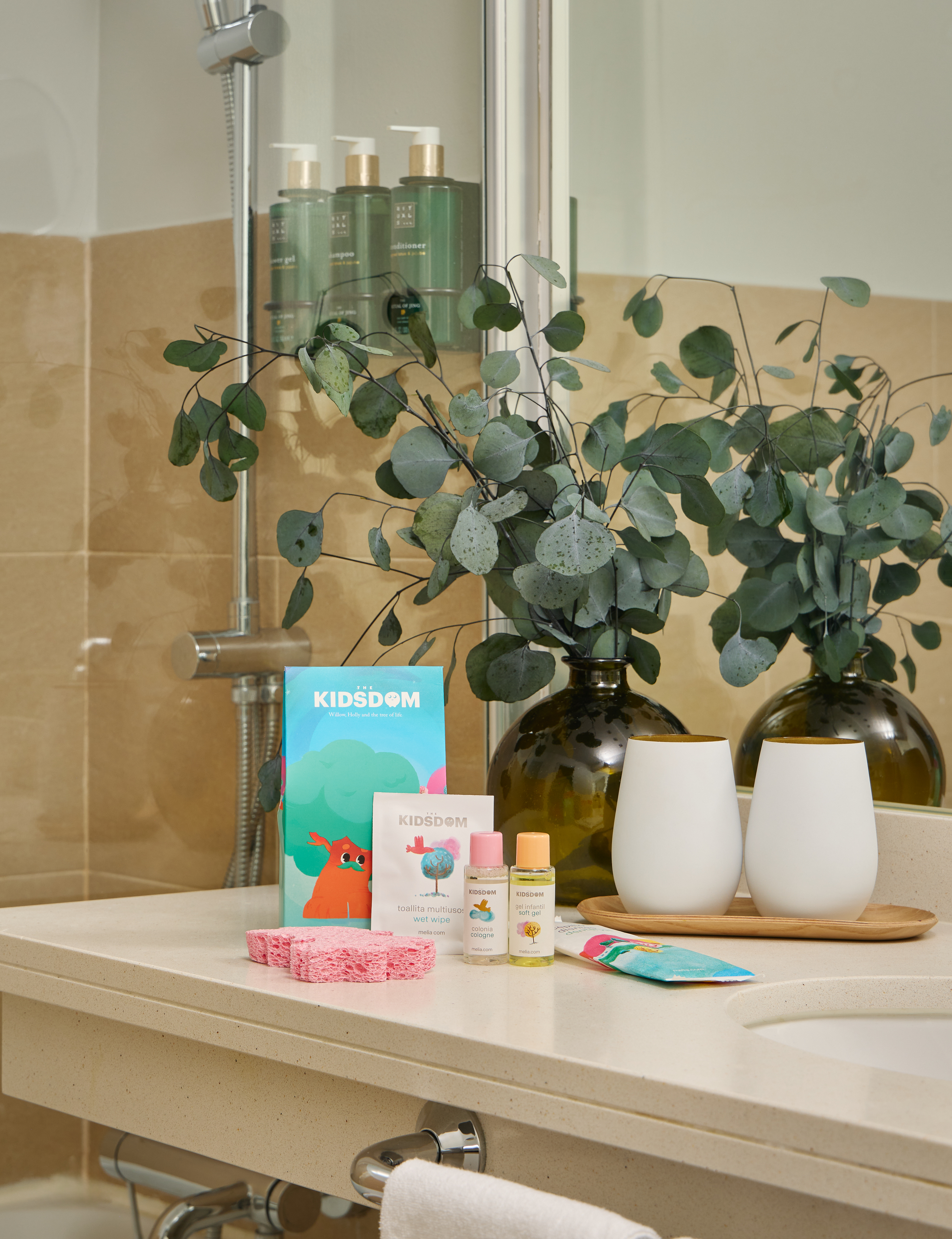 Hotel bathroom counter with Kidsdom kit, Rituals toiletries, and eucalyptus.