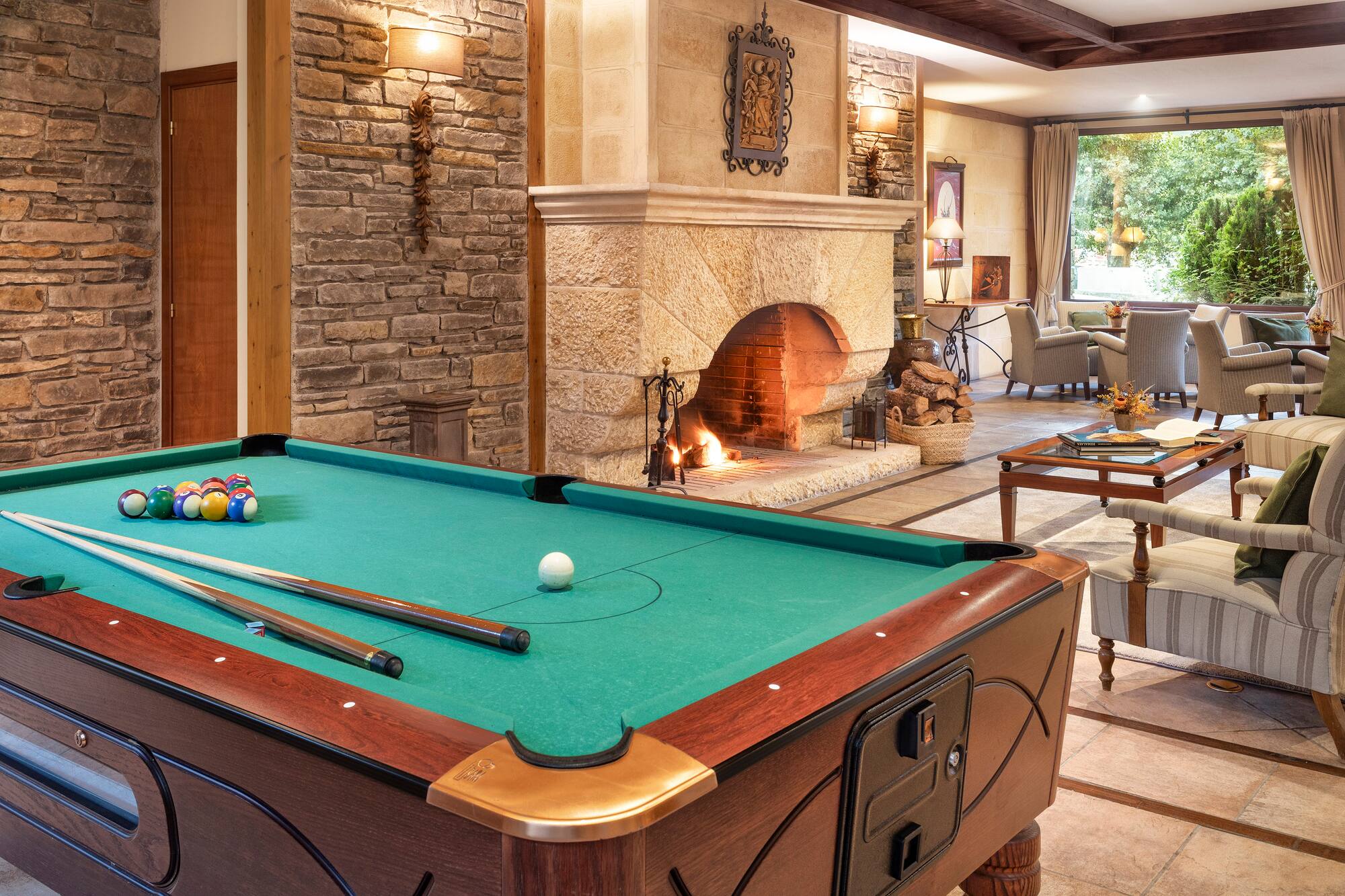 Cozy lodge game room with pool table, stone fireplace, and lounge seating.