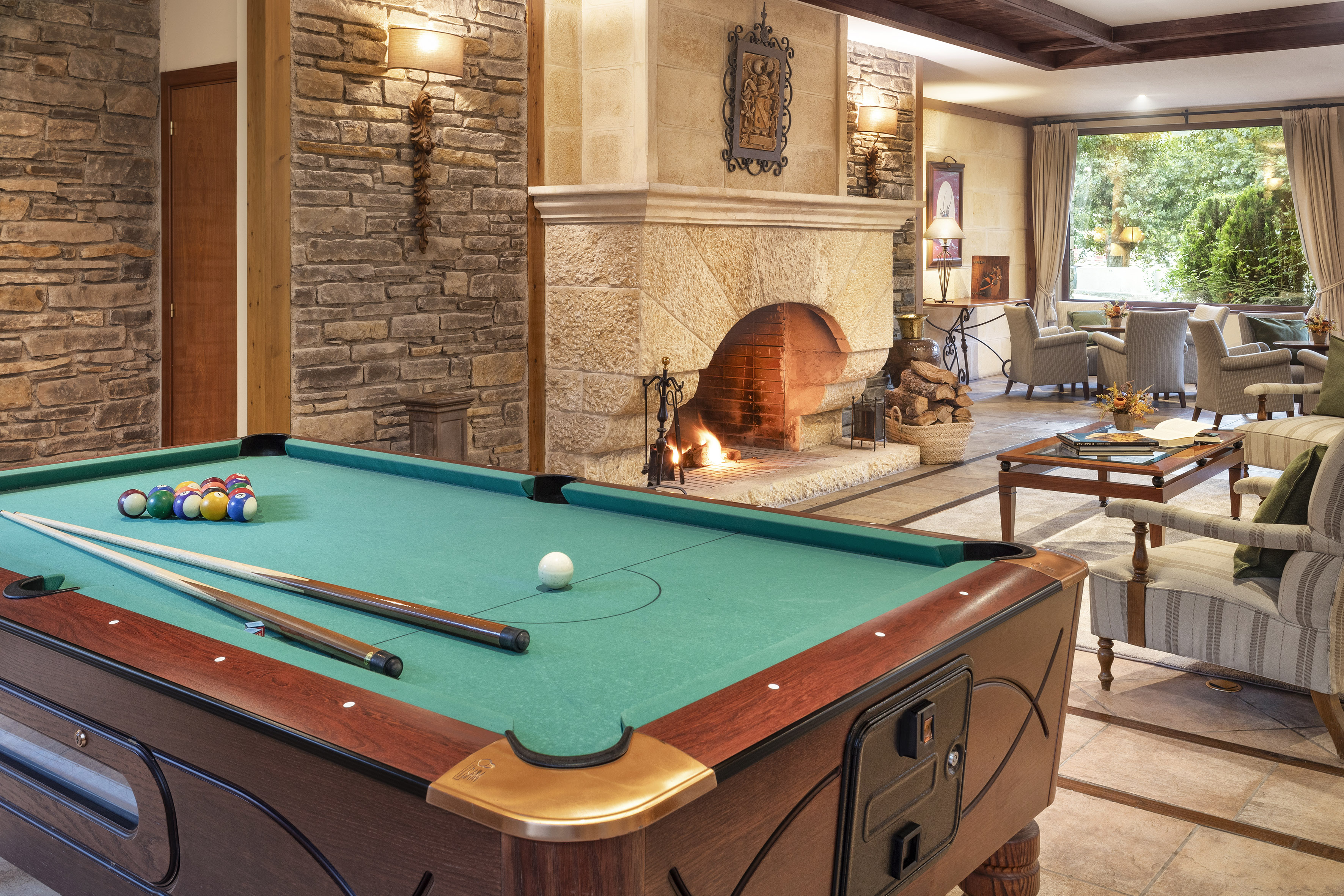 Cozy lodge game room with pool table, stone fireplace, and lounge seating.