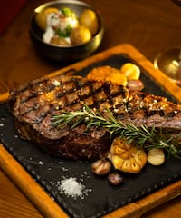 a steak on a plate with rosemary and garlic