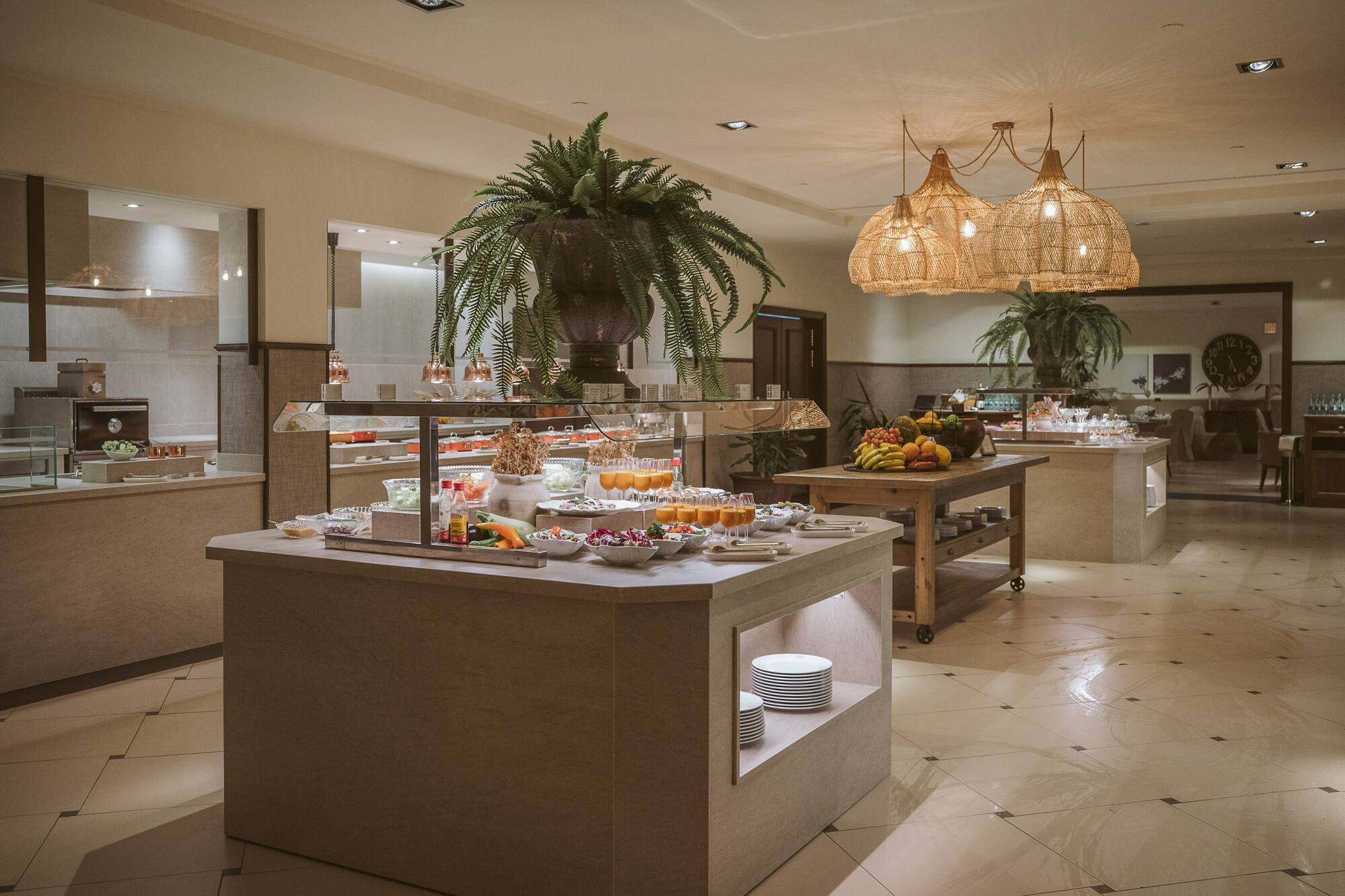 Elegant hotel buffet with fresh salads, juices, fruit, and modern decor.