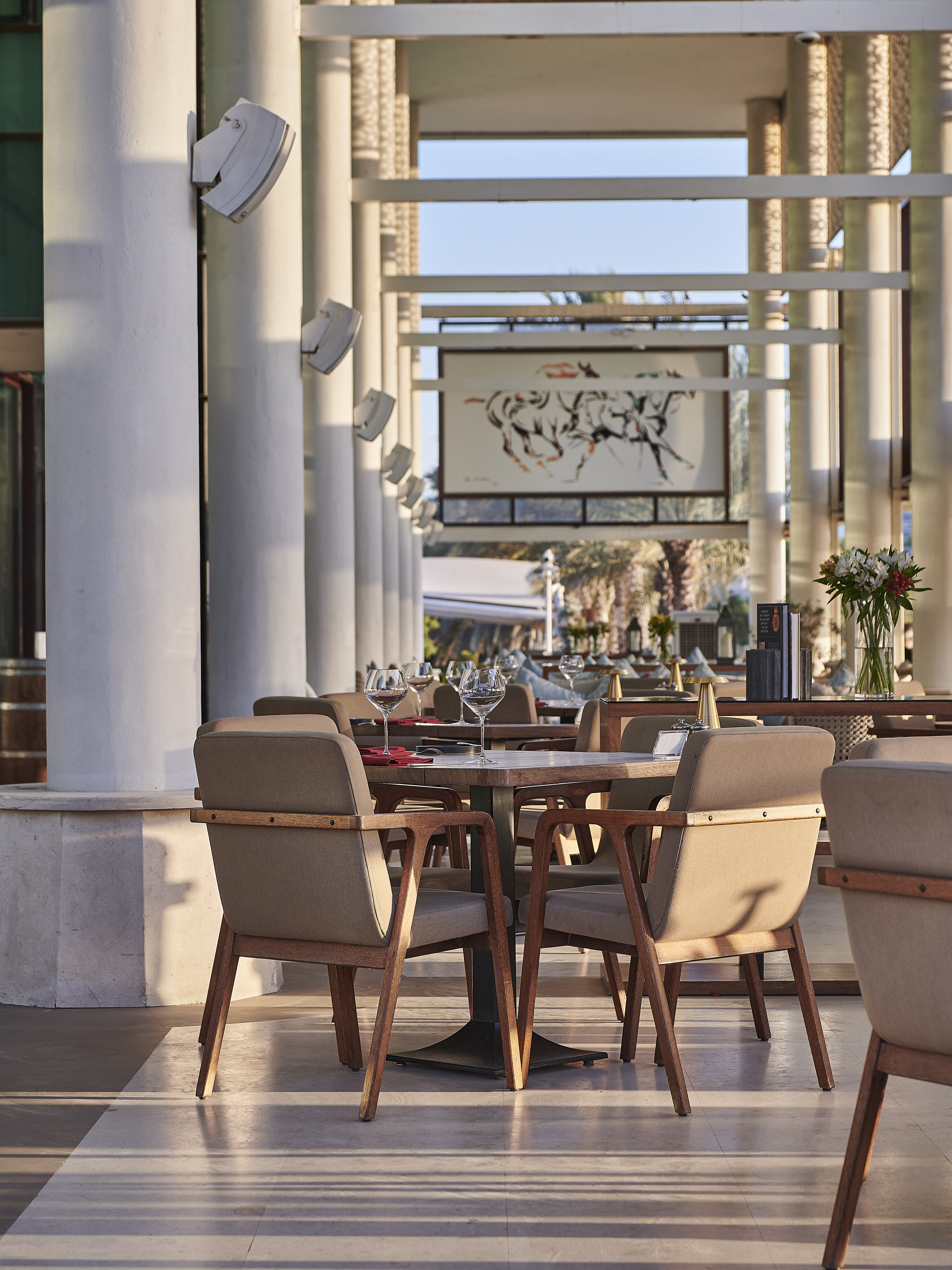 Elegant outdoor restaurant patio with tables, chairs, and architectural pillars.