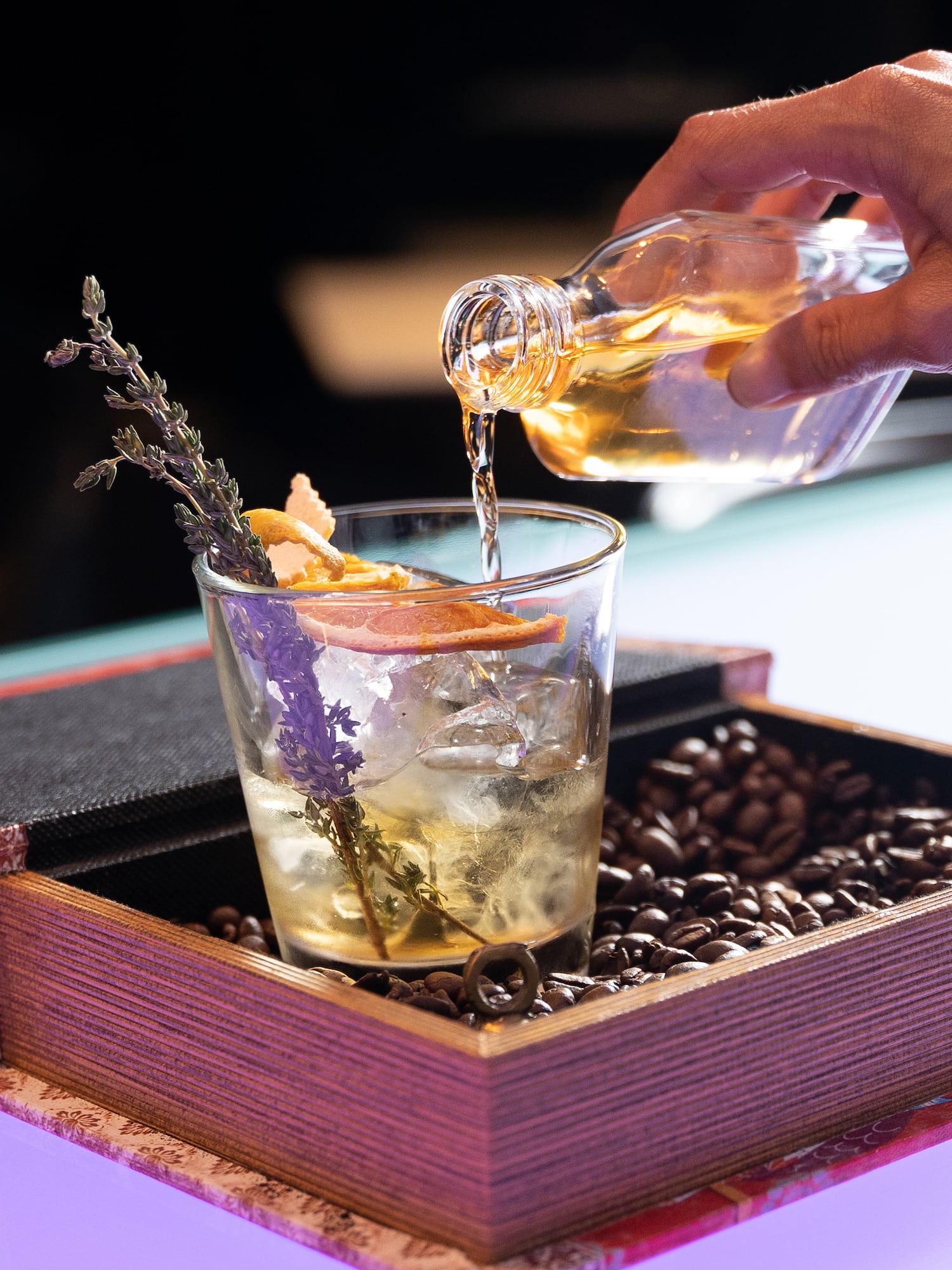a hand pouring liquid into a glass of drink
