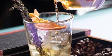 a hand pouring liquid into a glass of drink