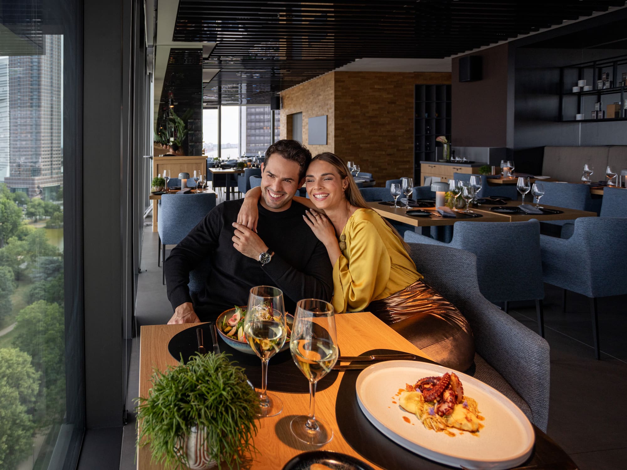 A man and a woman sit at a table filled with food and drinks.