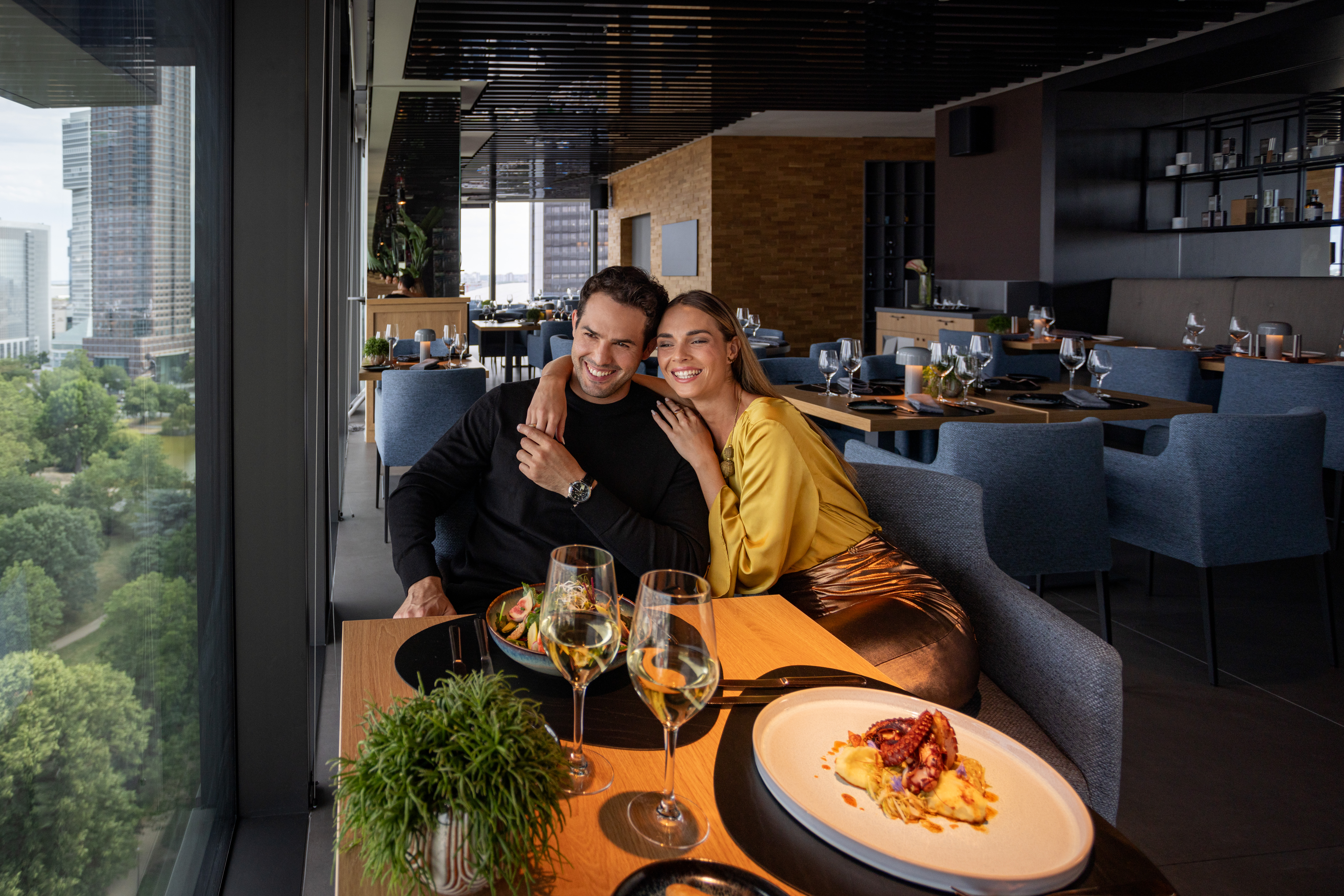 A man and a woman sit at a table filled with food and drinks.