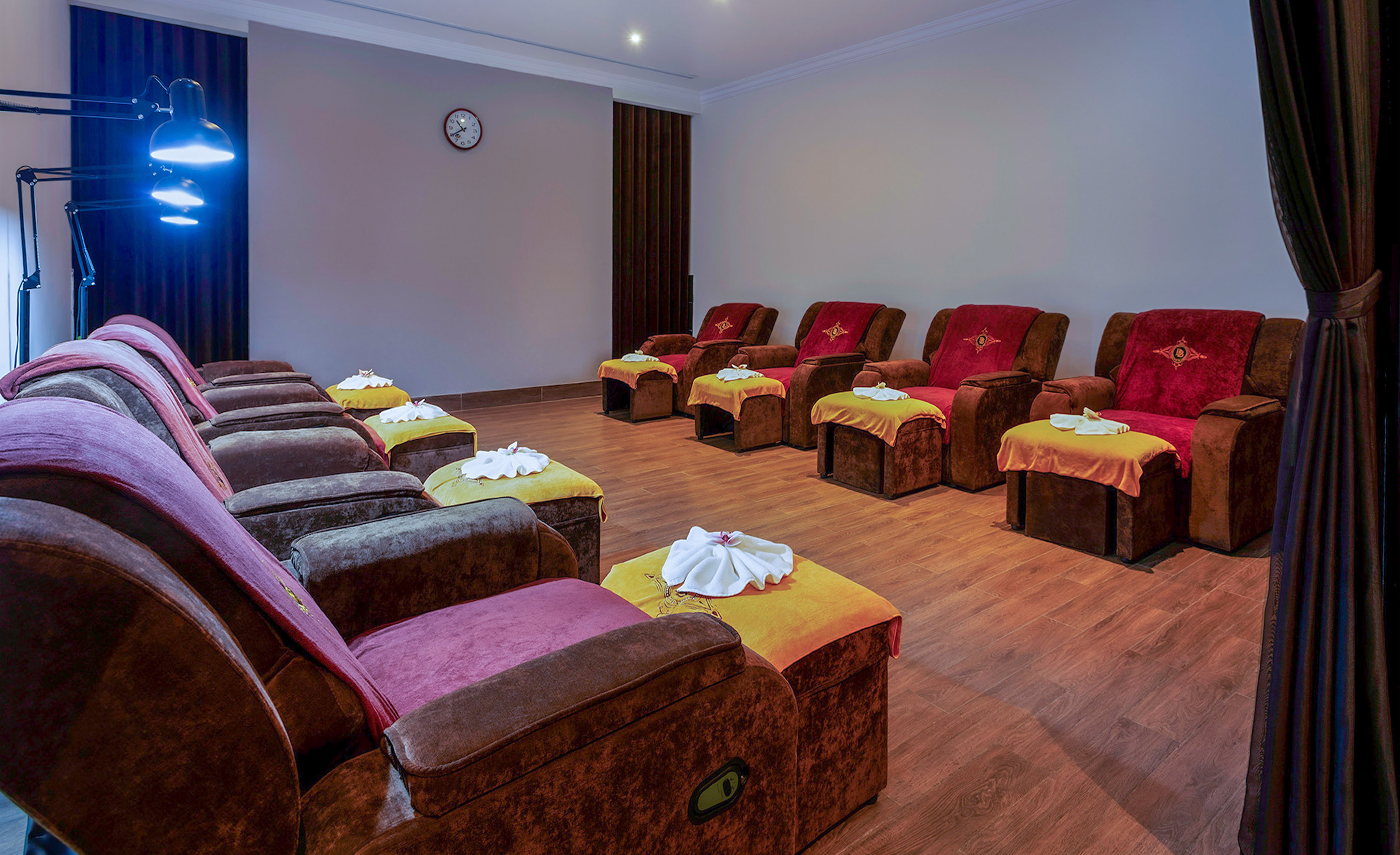 Foot massage spa room with rows of plush recliners and footrests.