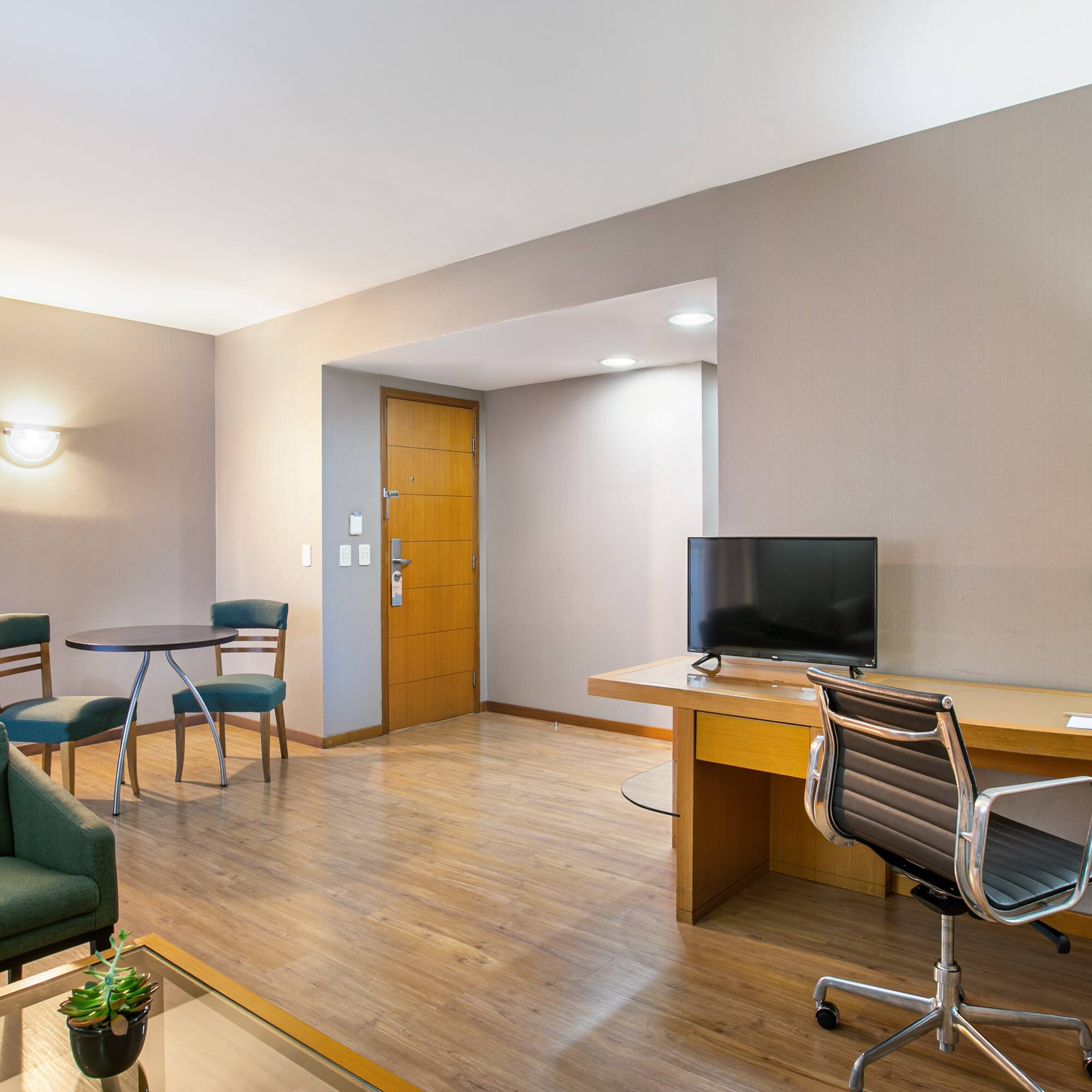 Contemporary hotel suite with living area, desk, and kitchenette.