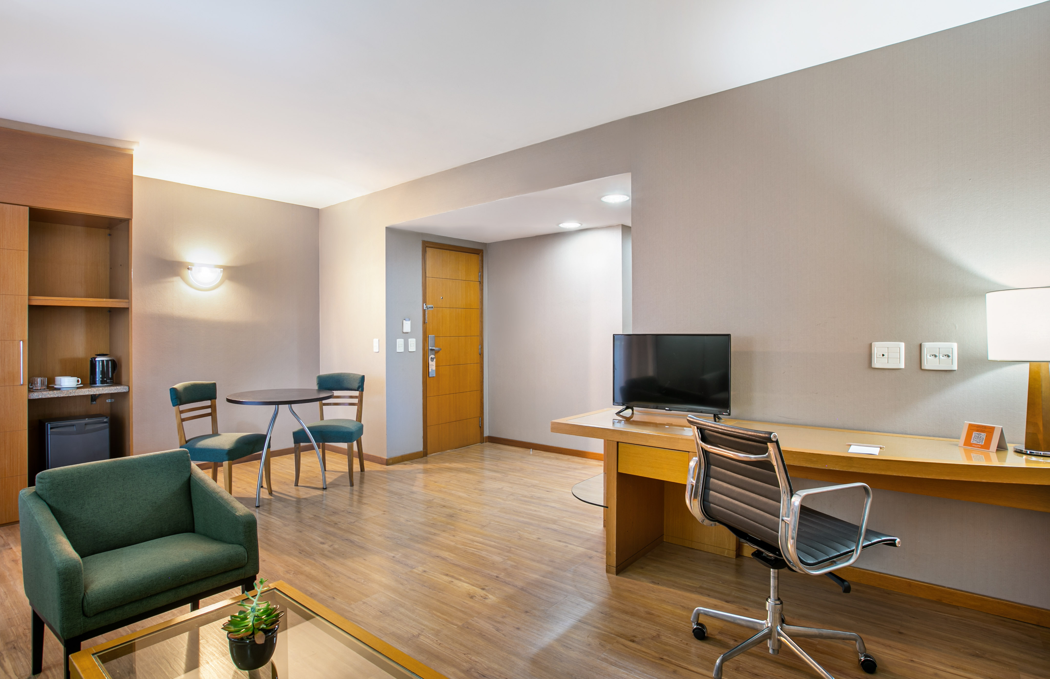 Contemporary hotel suite with living area, desk, and kitchenette.