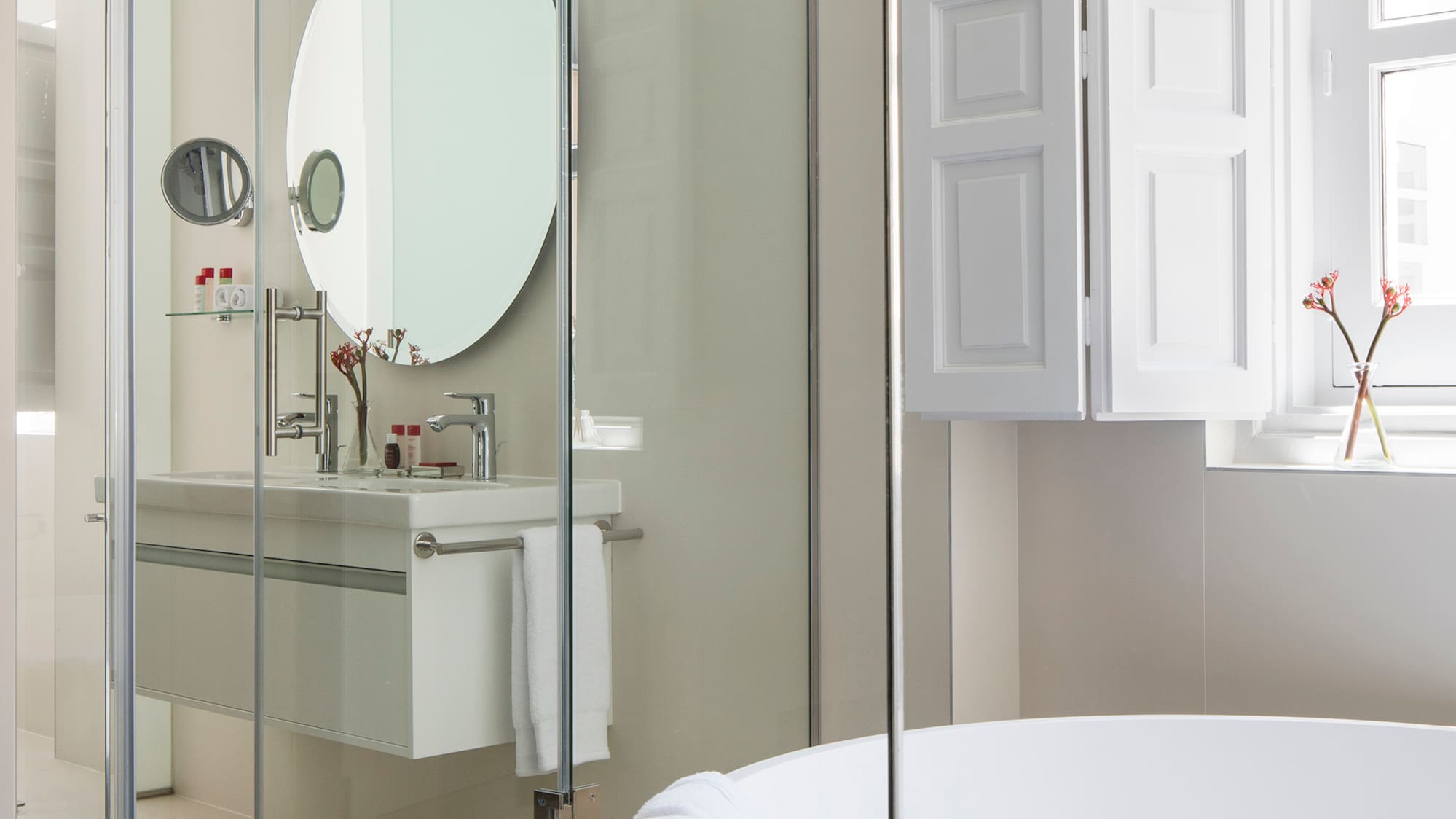 a bathroom with a round mirror and a tub