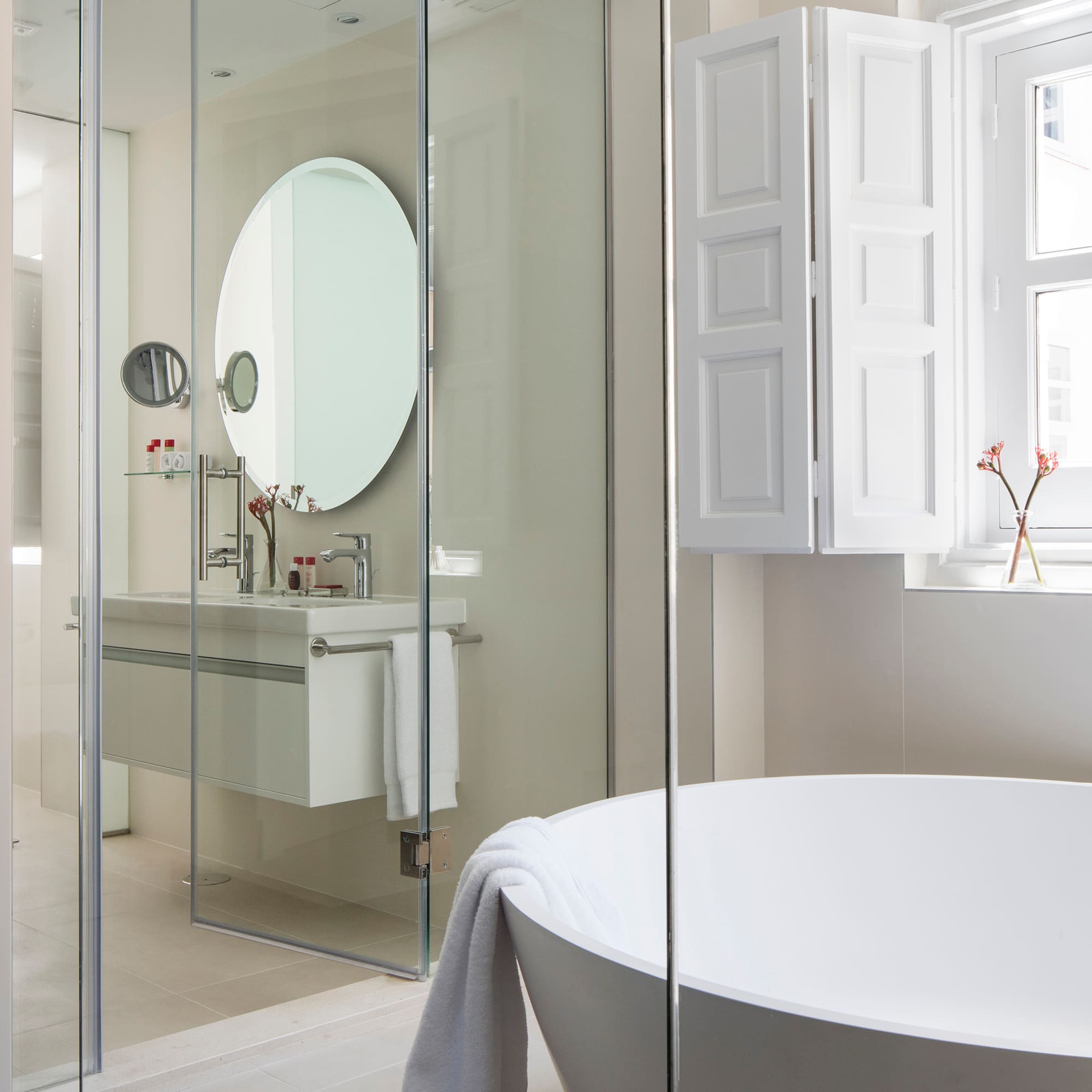 a bathroom with a round mirror and a tub
