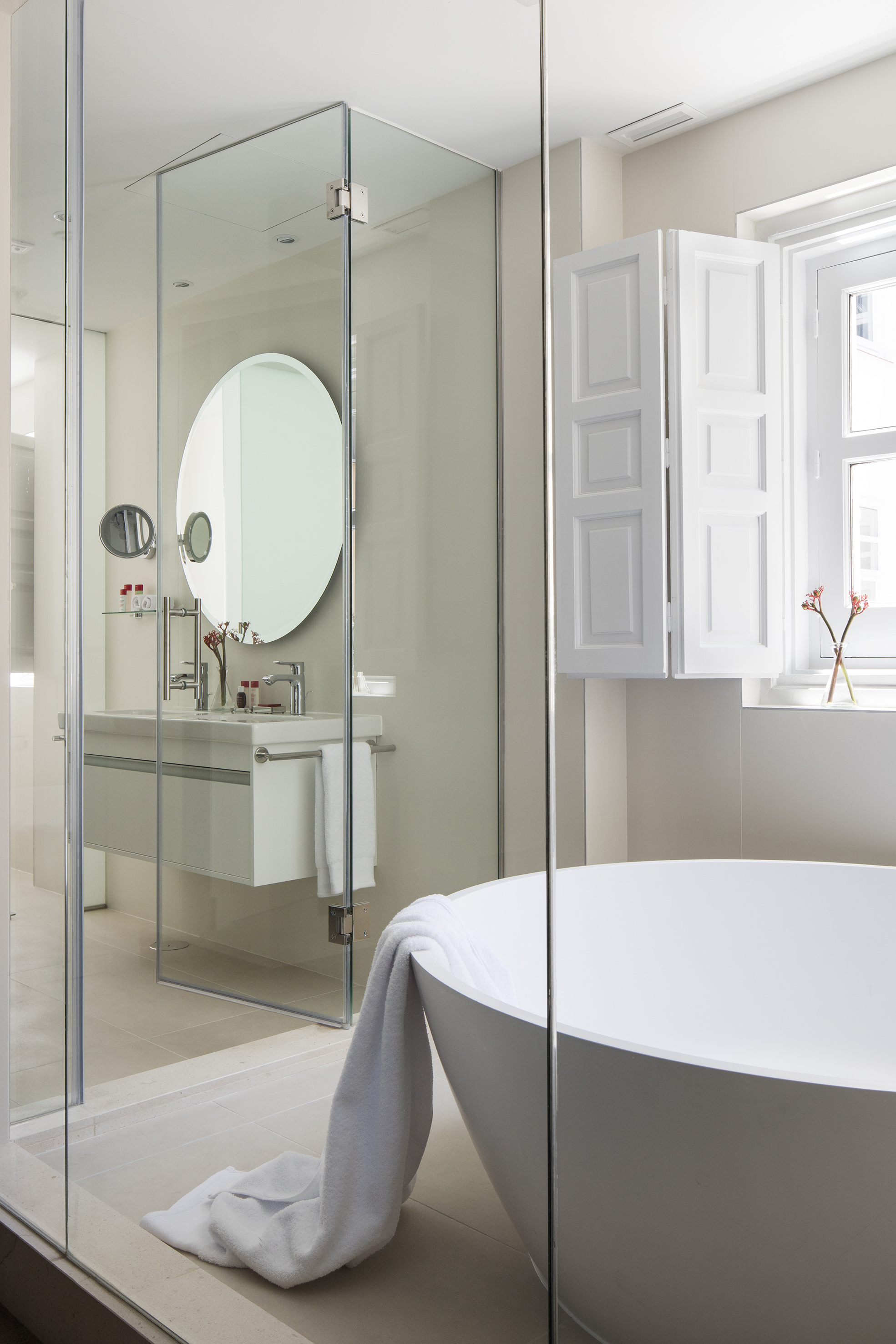 a bathroom with a round mirror and a tub