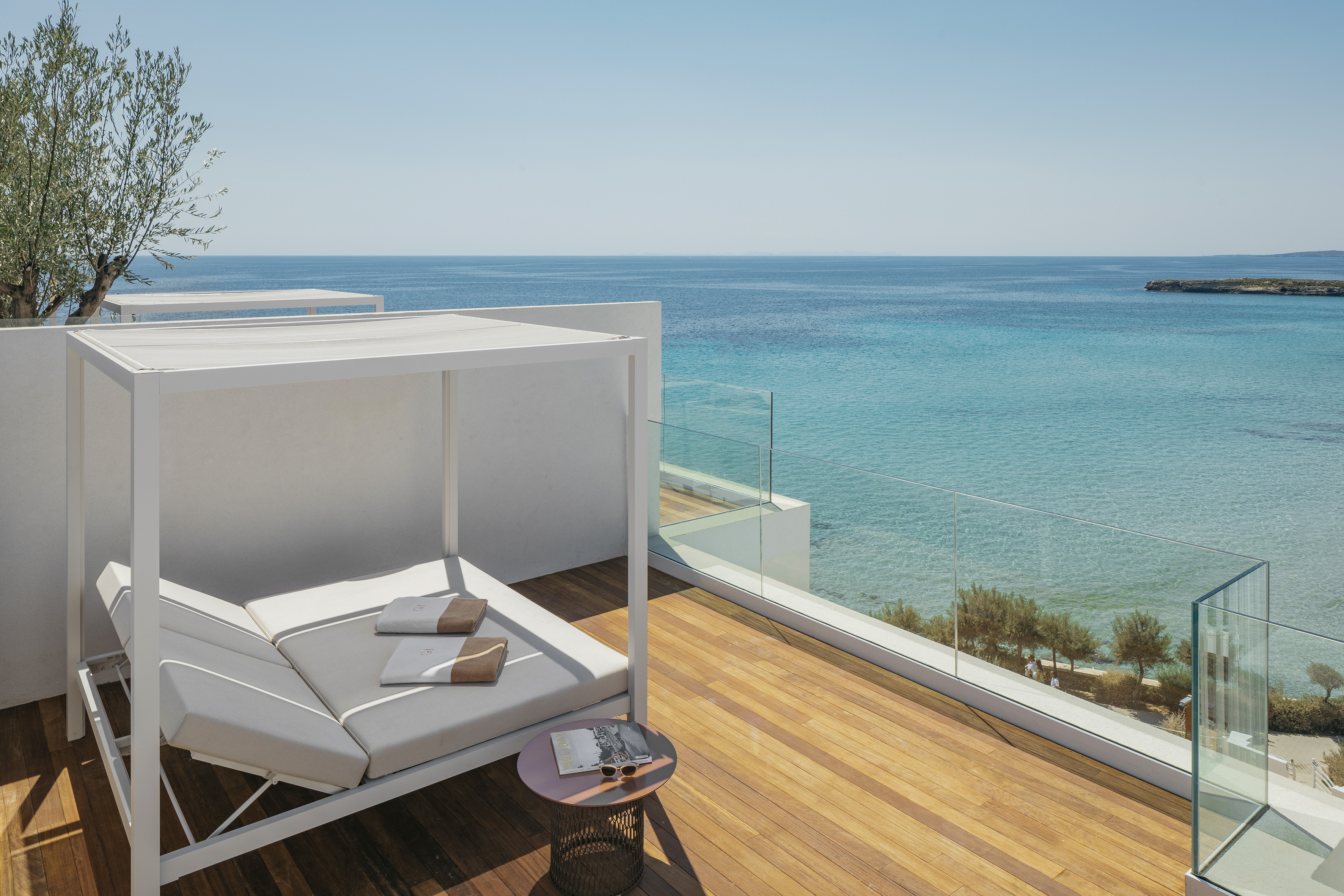 Luxury hotel balcony with daybed, wooden deck, and blue ocean view