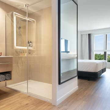 a bathroom with a glass shower and a bed