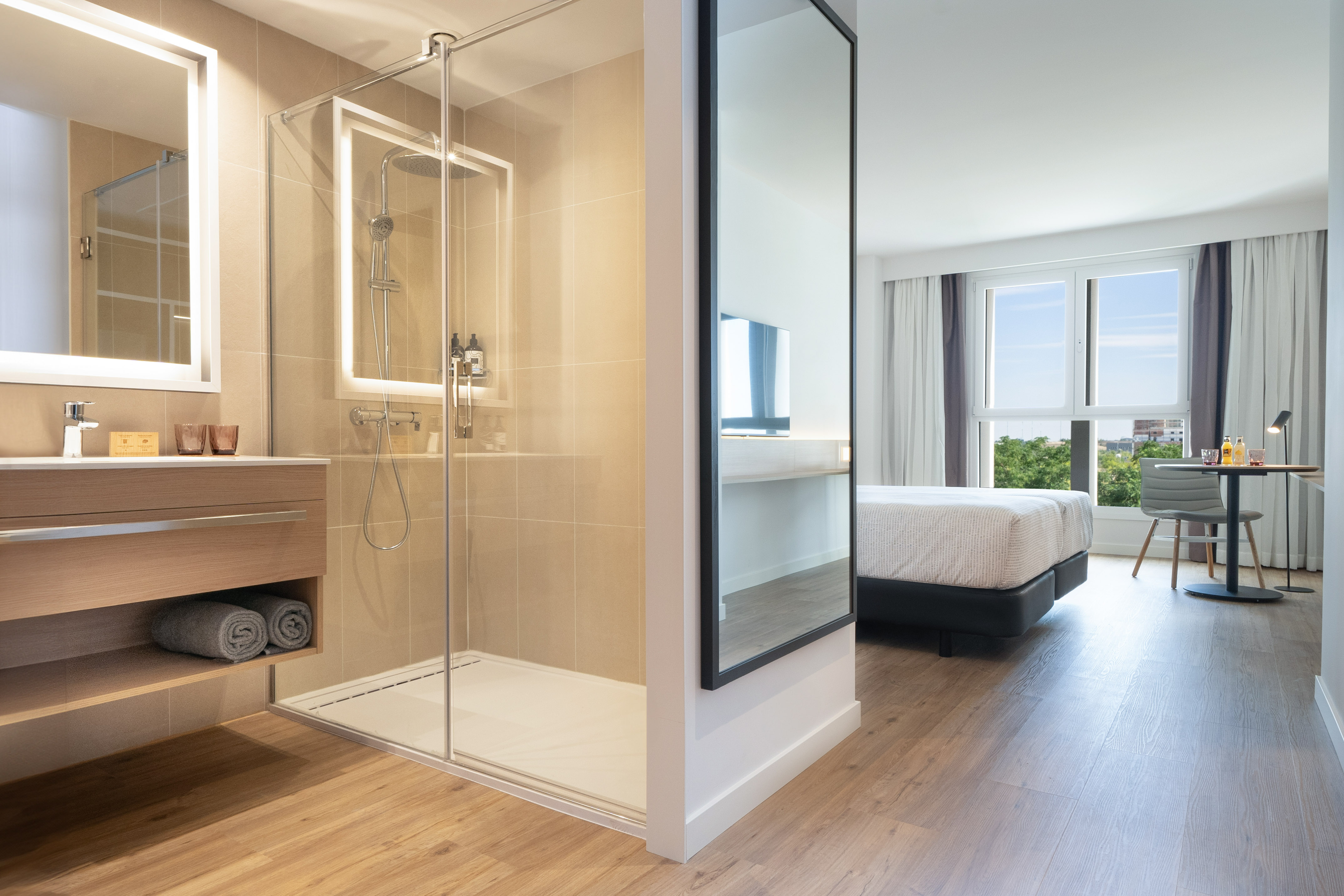 Contemporary hotel room: modern bathroom with walk-in shower, bright bedroom.