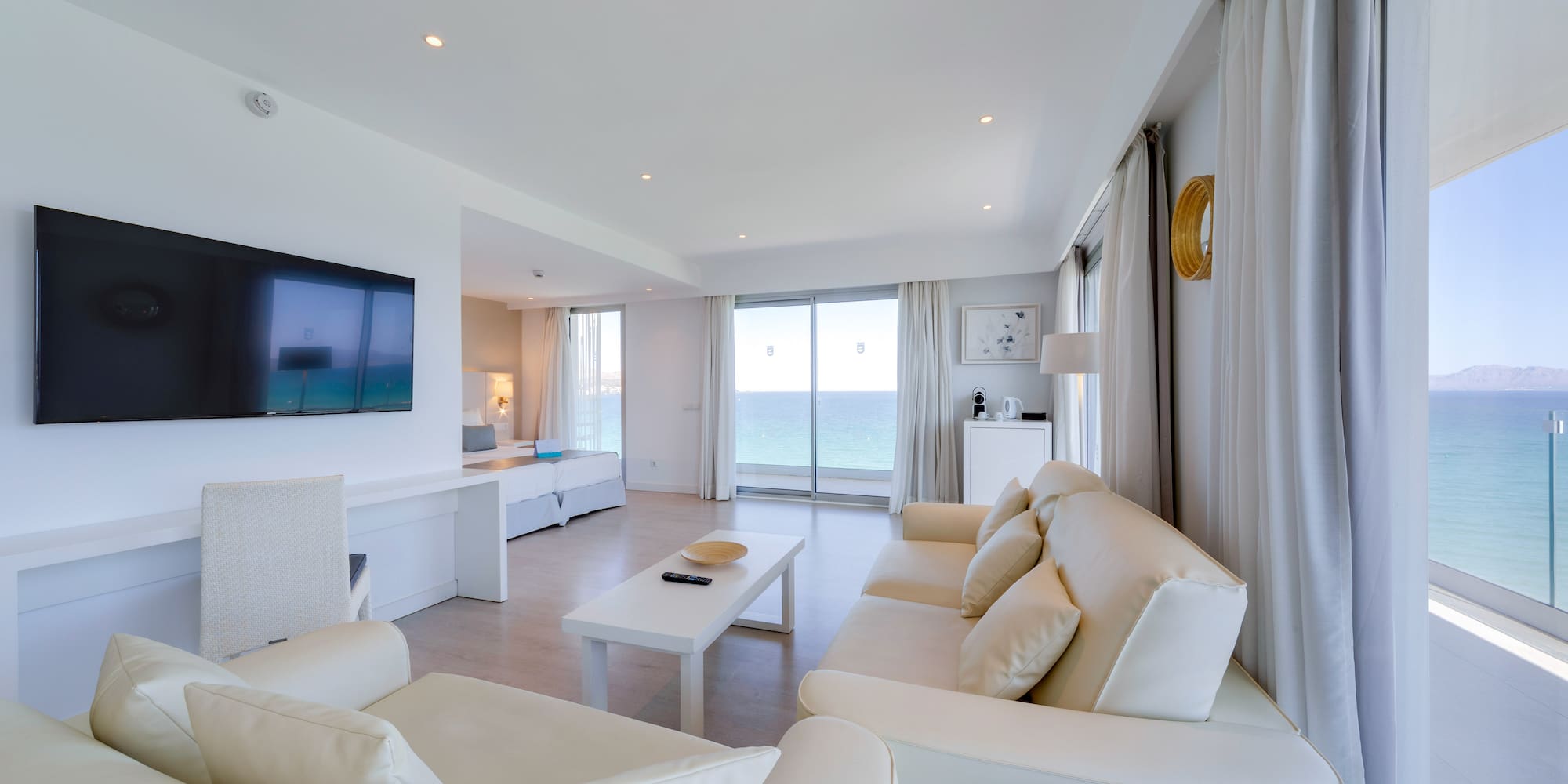 a living room with white furniture and a television