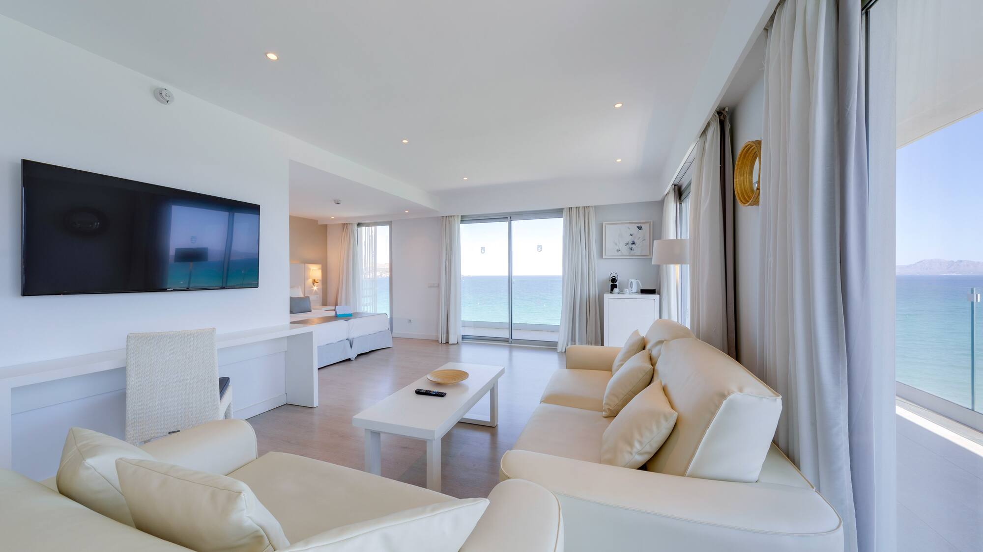 a living room with white furniture and a television