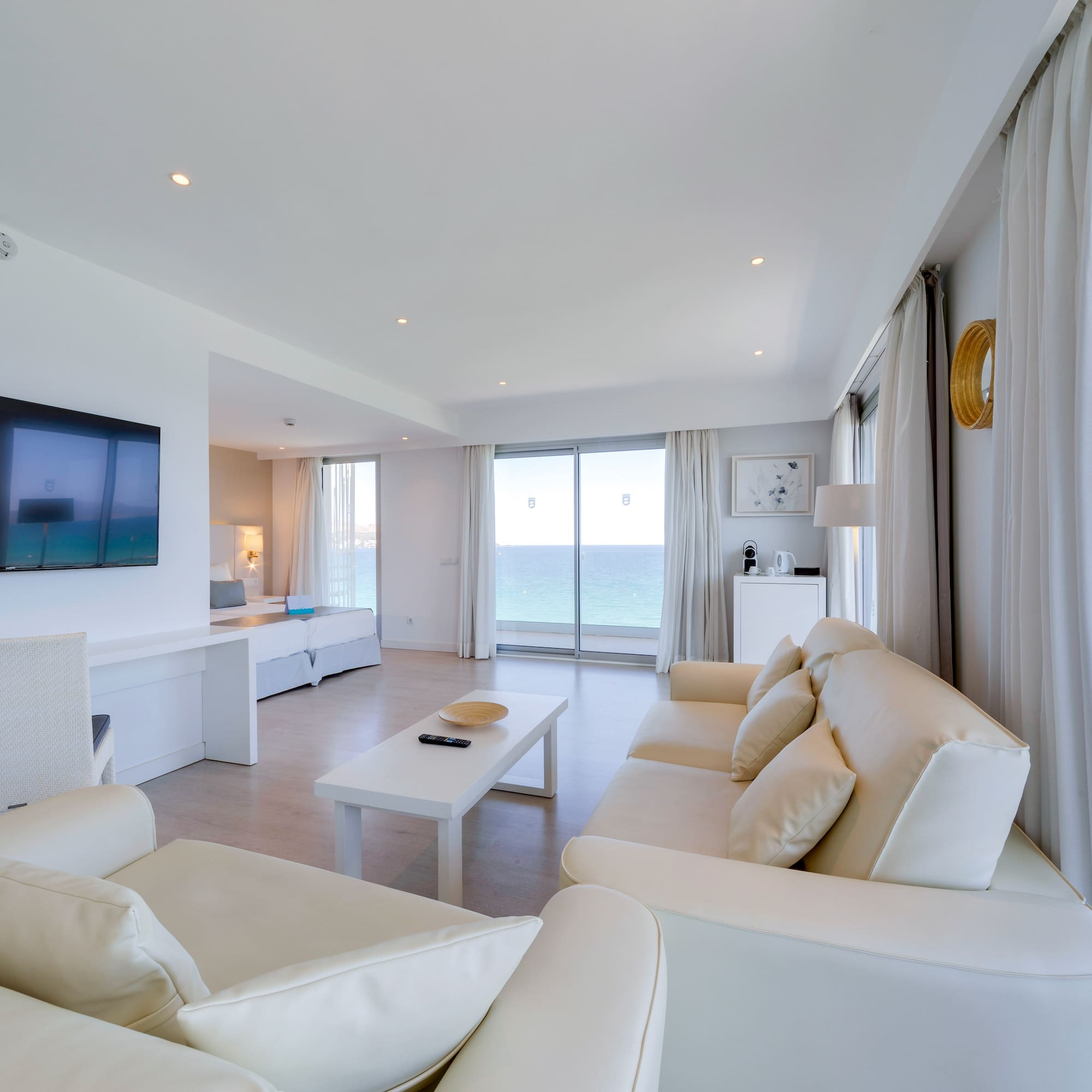 a living room with white furniture and a television