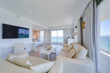 a living room with white furniture and a television