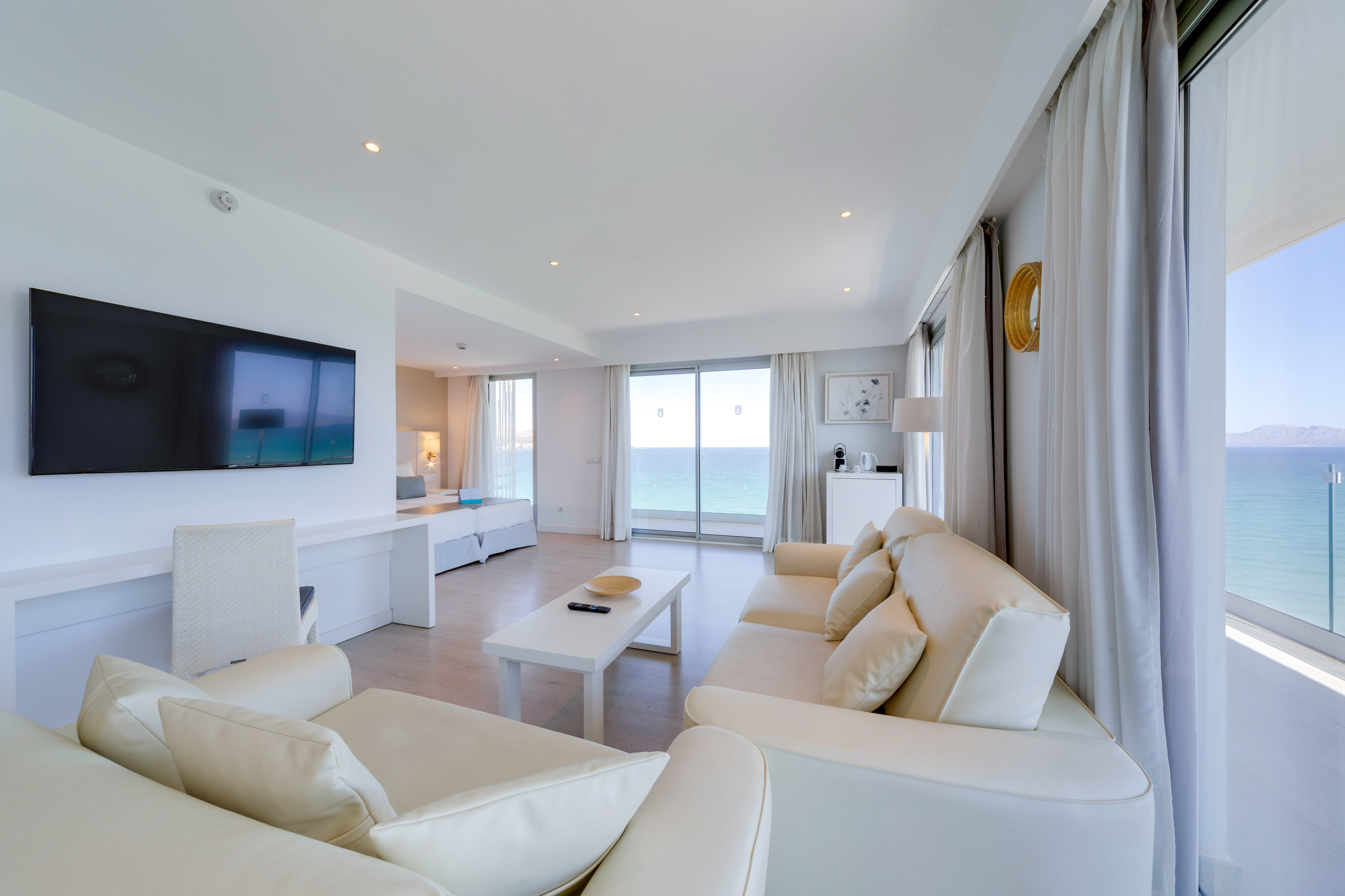 a living room with white furniture and a television