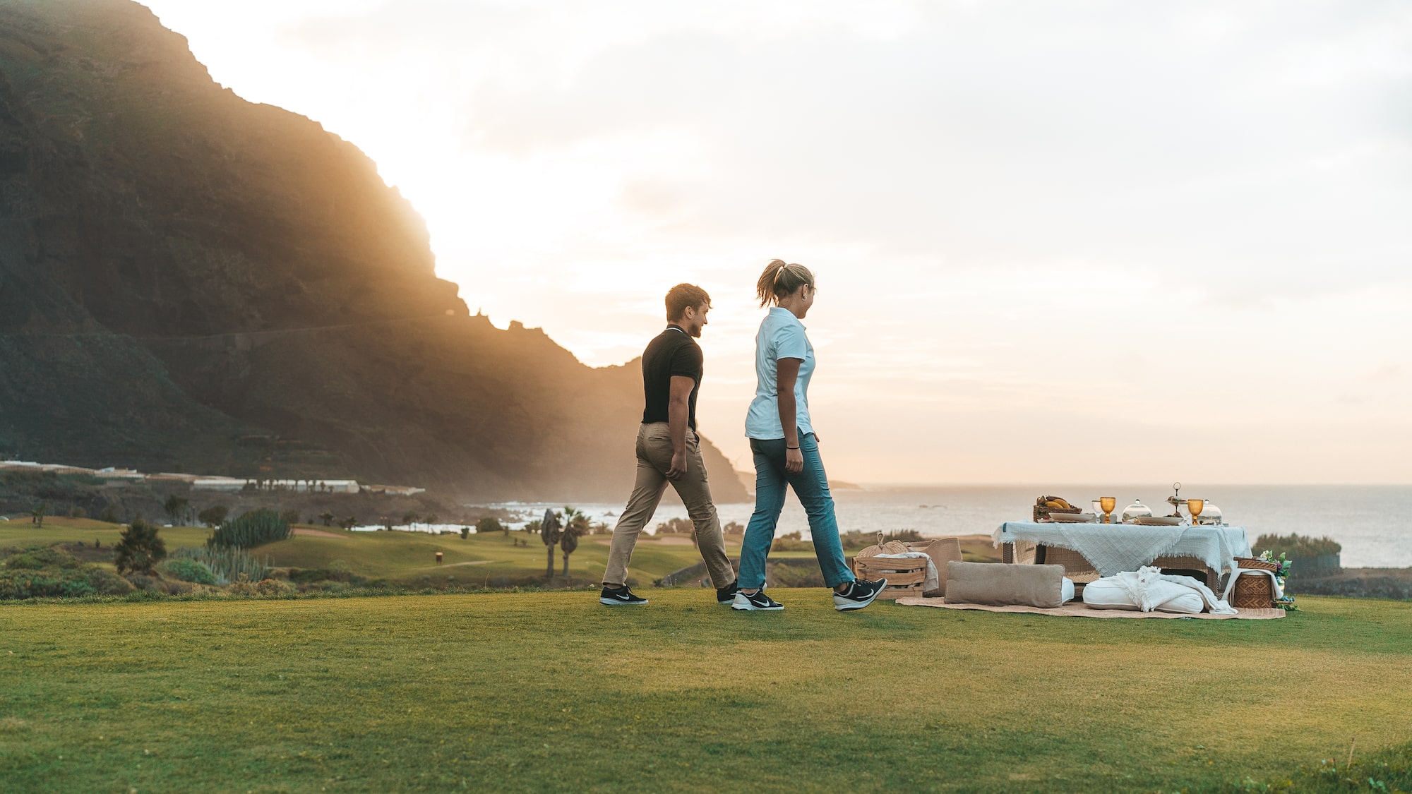 a man and woman walking on a grassy hill