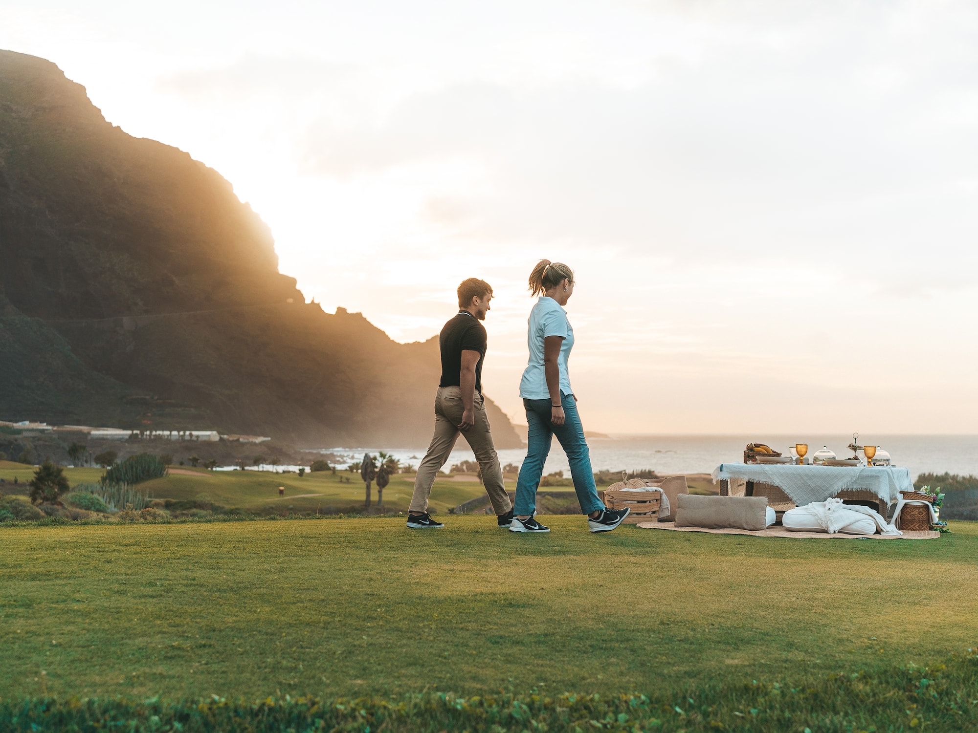 a man and woman walking on a grassy hill