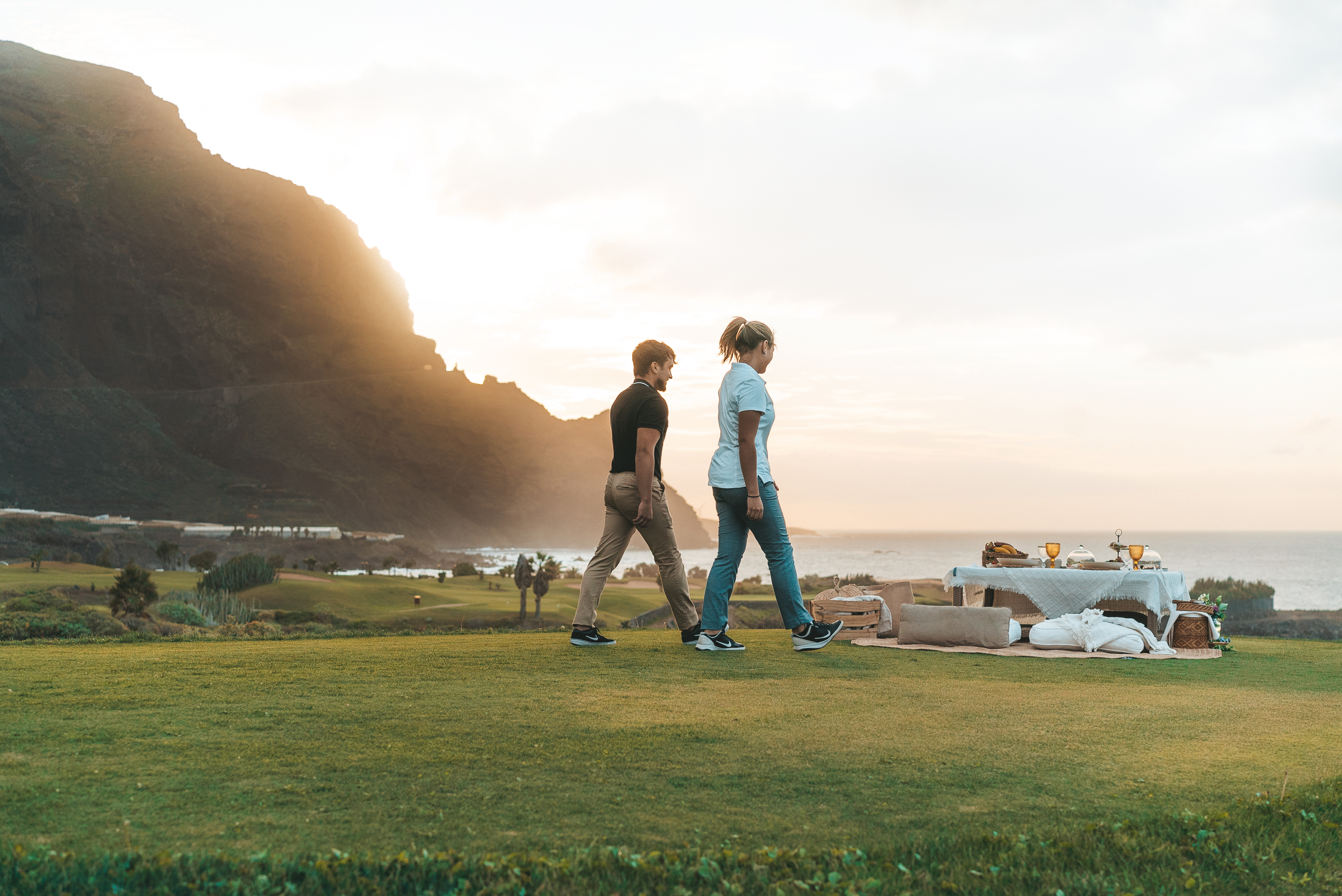 a man and woman walking on a grassy hill