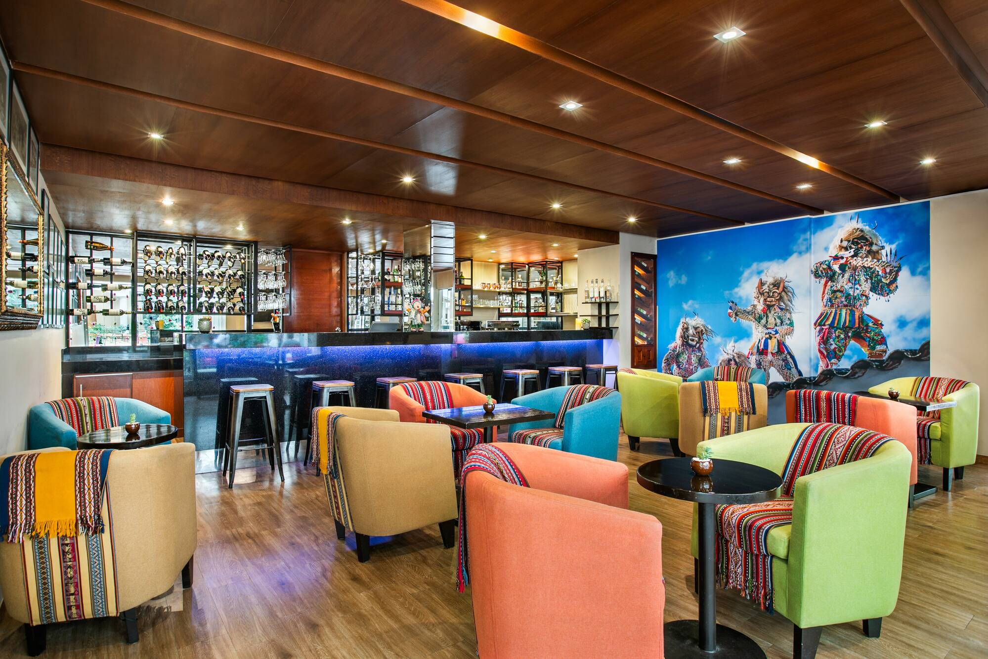 Vibrant lounge bar with colorful chairs, Peruvian textiles, and cultural mural. - Hotel Cusco La Paccha Affiliated by Meliá, Cusco