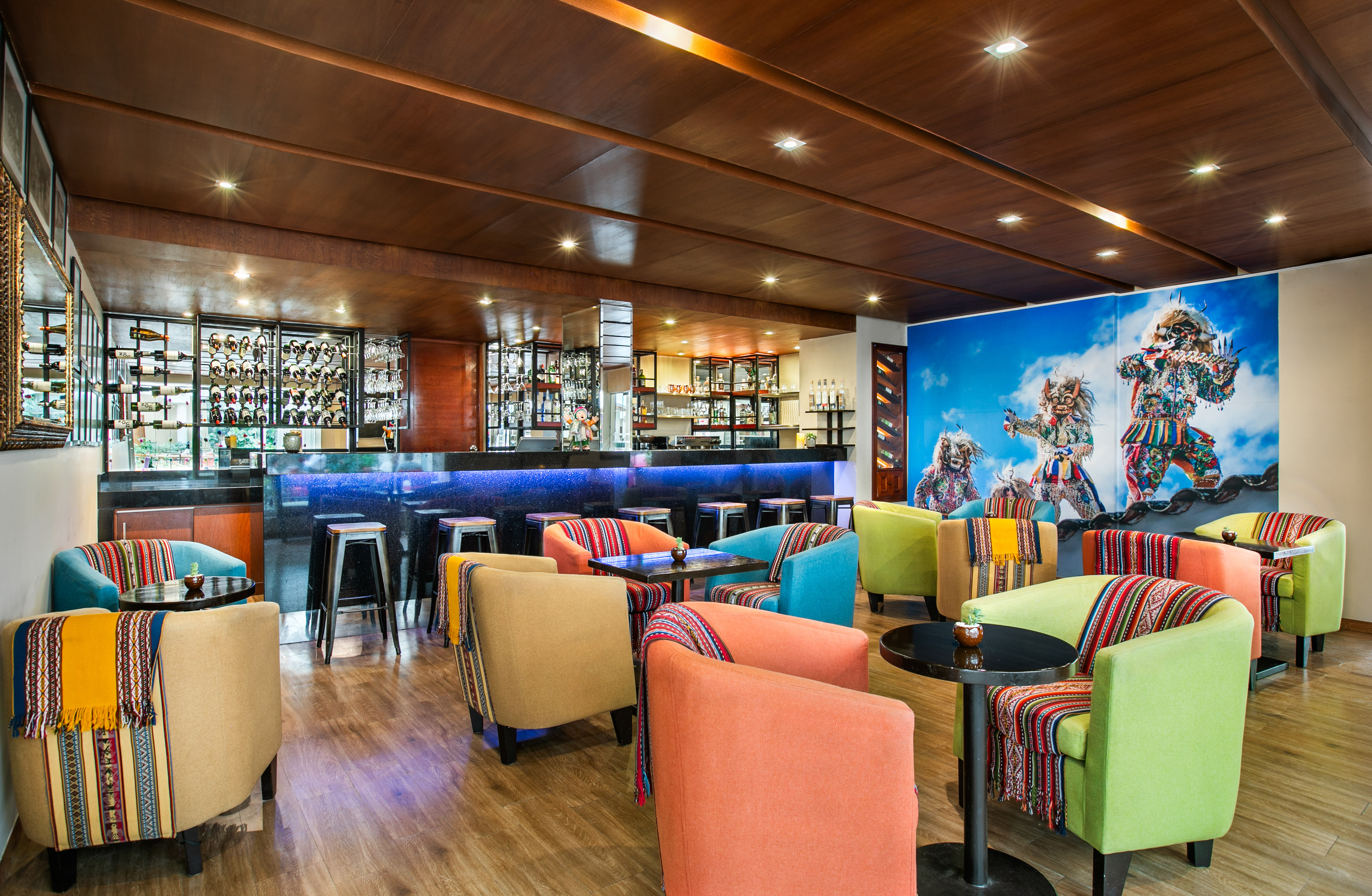 Vibrant lounge bar with colorful chairs, Peruvian textiles, and cultural mural.