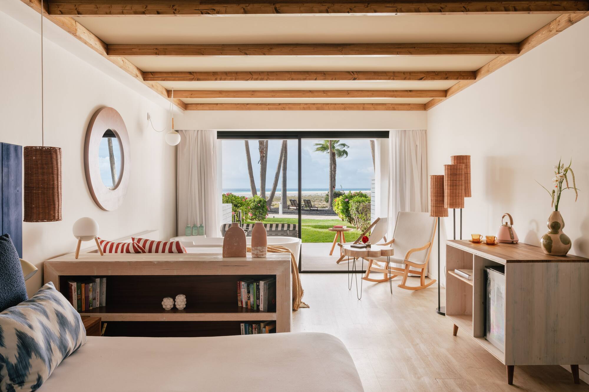 Oceanfront hotel room with modern decor, beach view, and exposed wood beams.