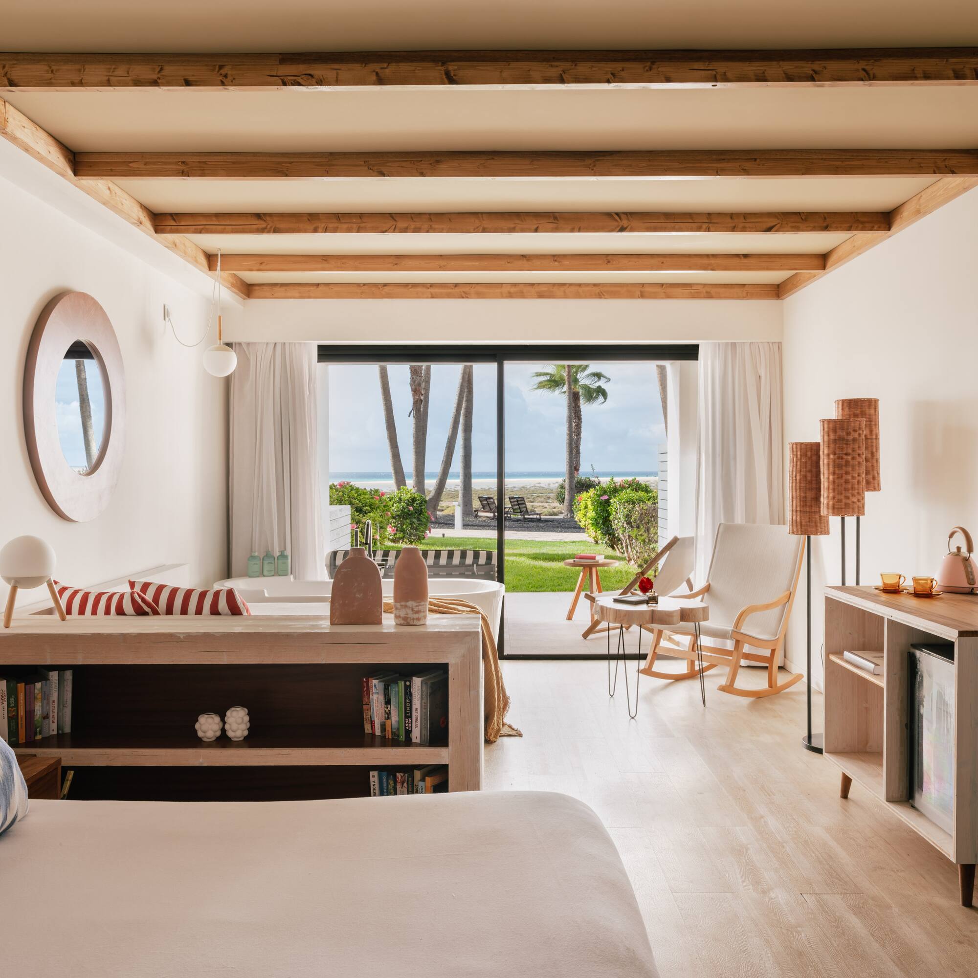 Oceanfront hotel room with modern decor, beach view, and exposed wood beams.